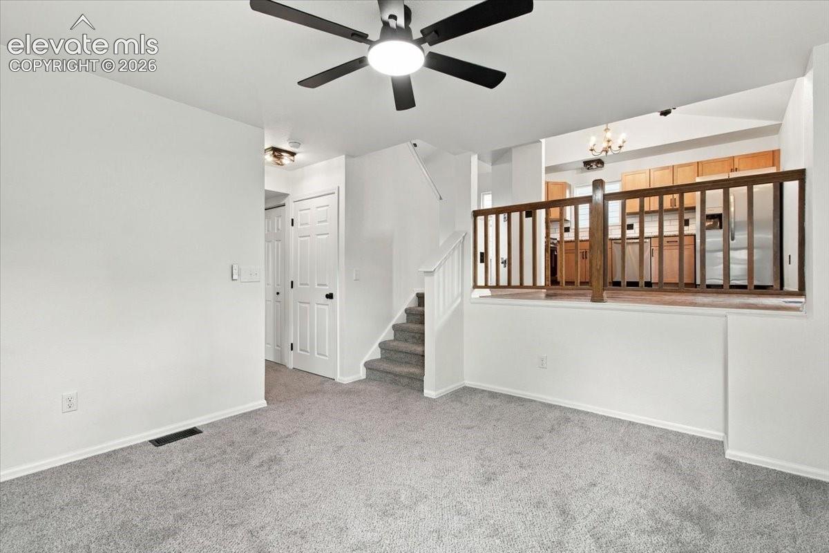 Carpeted flooring, multi-level layout featuring a wooden balustrade, ceiling fan with integrated lighting, and interior six-panel doors