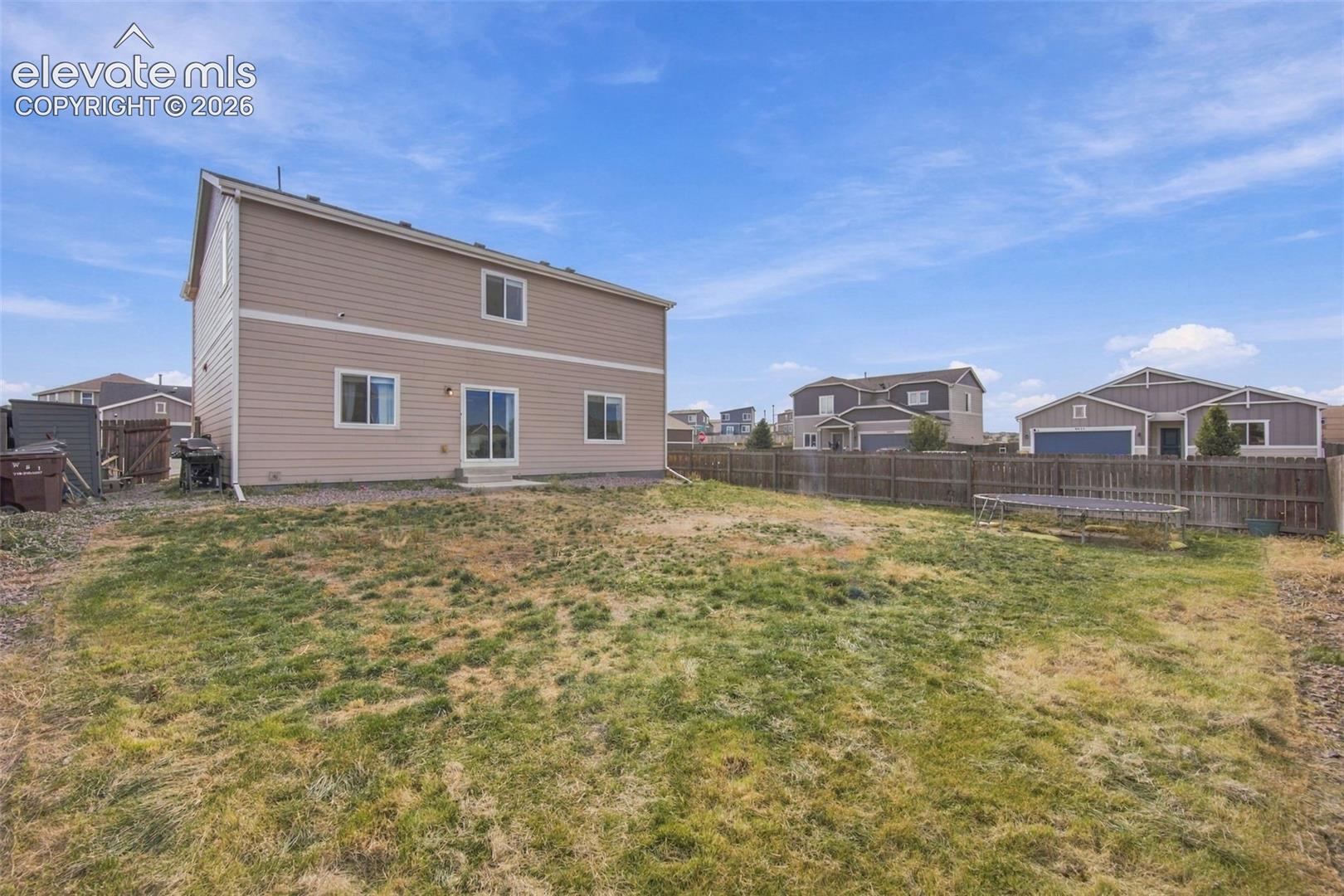 Two-story exterior with horizontal siding, sliding glass door, and fenced backyard