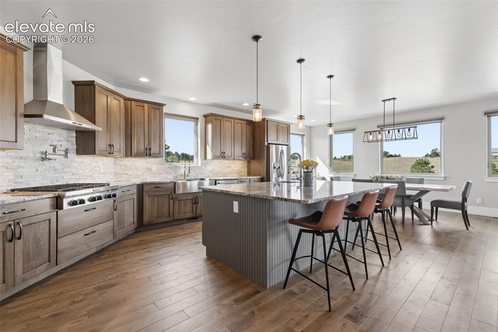 Gourmet kitchen featuring wood-finish cabinetry, stainless steel appliances, a large island with a stone countertop, and wood-finish flooring