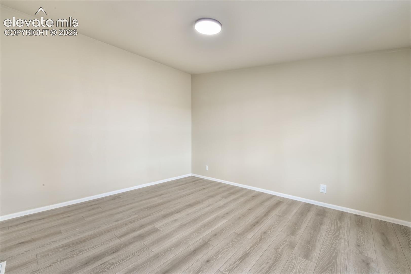 Wood-finish flooring, light neutral wall paint, and overhead flush-mount lighting