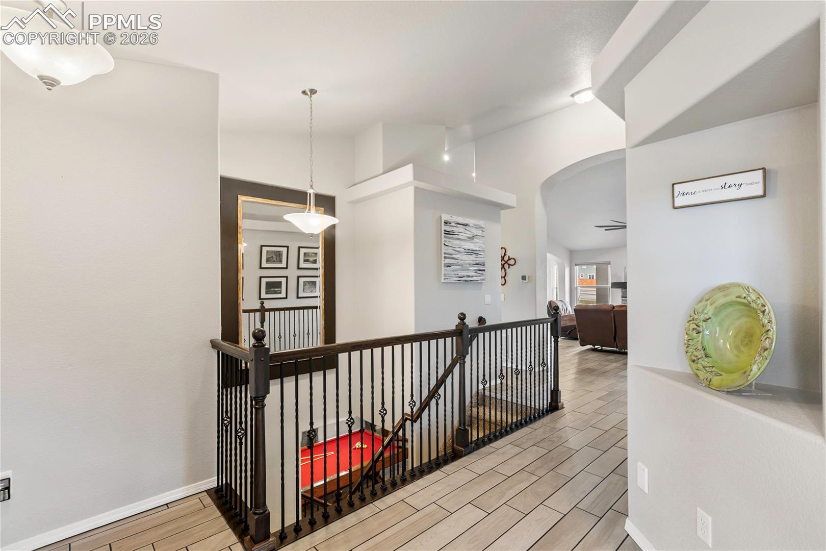 Entryway featuring ceramic tile flooring, wrought iron balusters, a dark wood newel posts, and a recessed niche