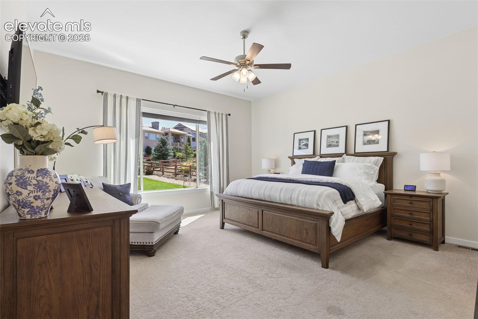Carpeted flooring featuring a ceiling fan, a large window, light-toned walls, and a built-in entertainment stand