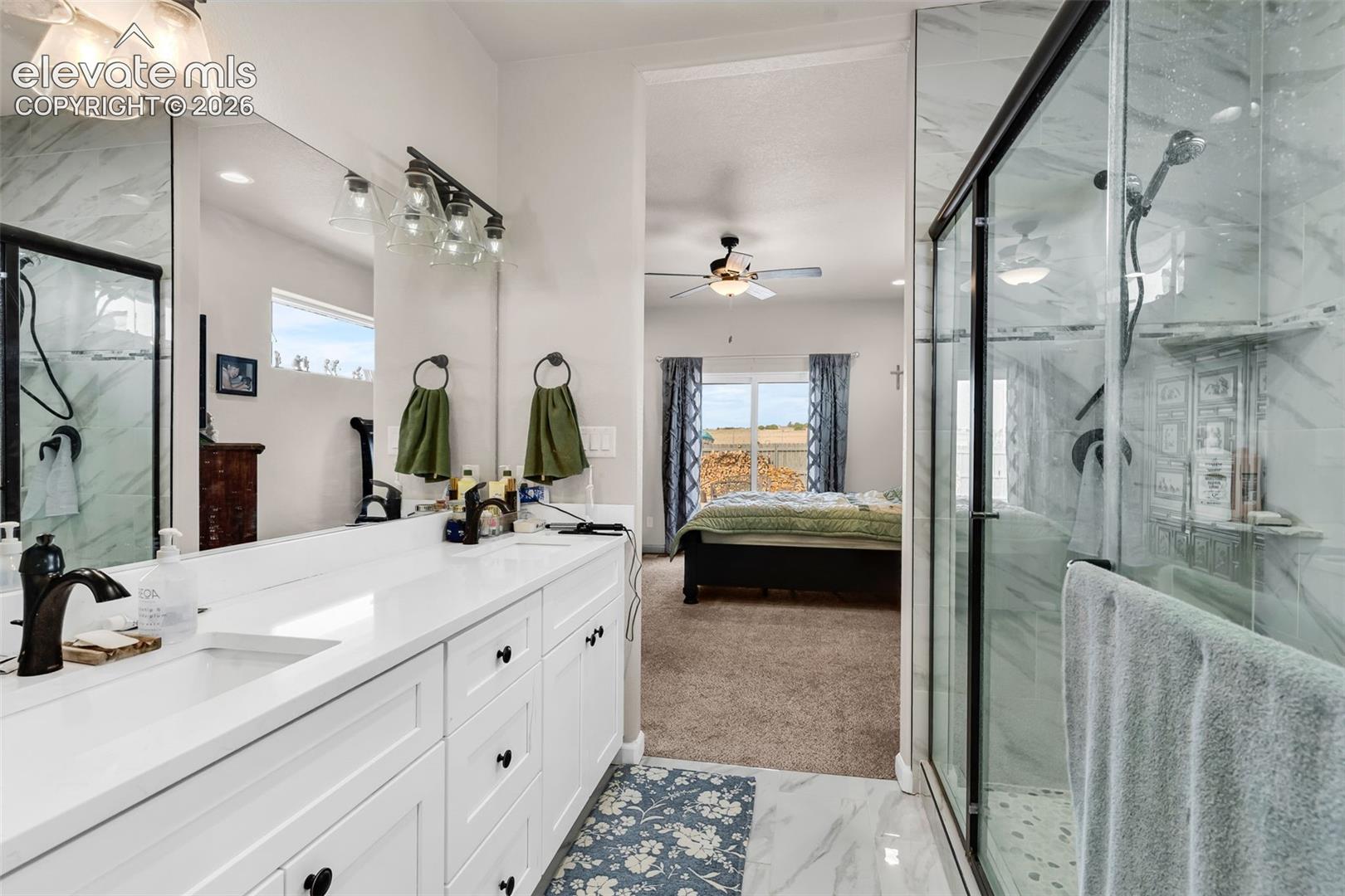 Dual vanity with white cabinetry and integrated sinks, glass-enclosed shower with tiled walls and built-in shelving, and white tile flooring