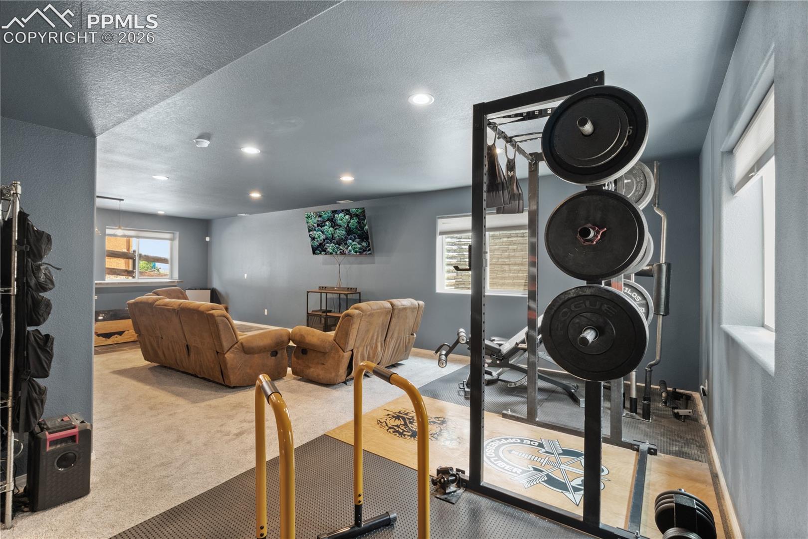Exercise room with light carpet, a textured ceiling, and recessed lighting
