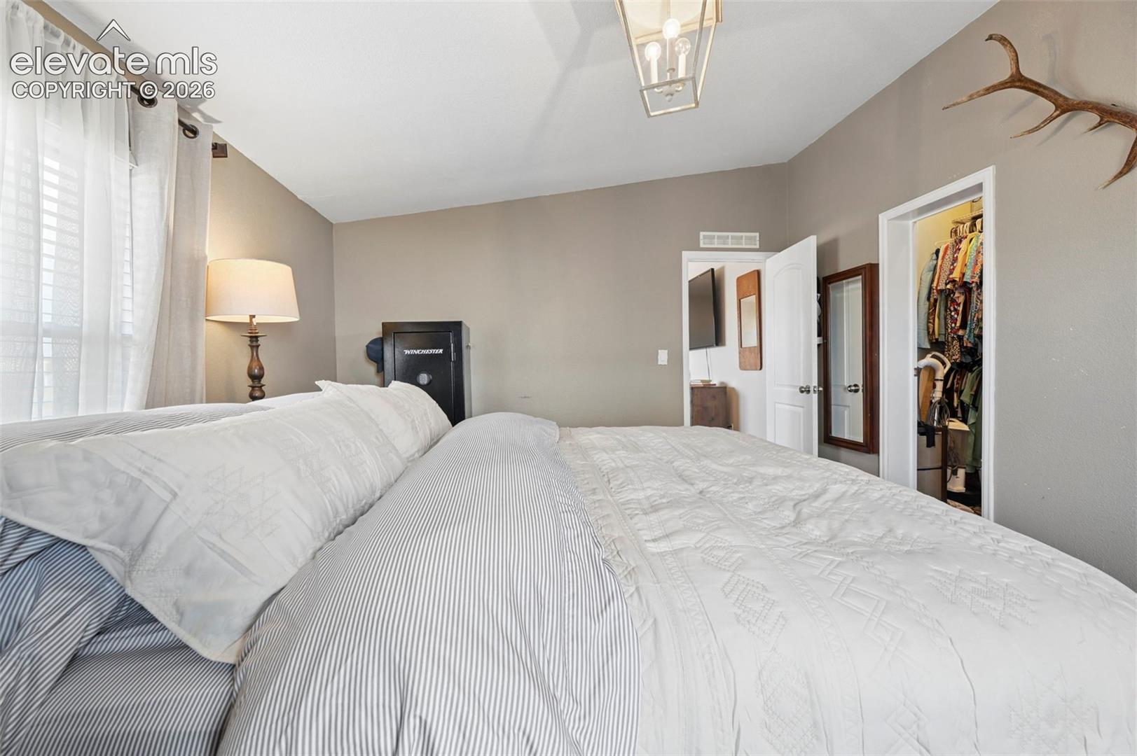 Bedroom featuring vaulted ceilings, a geometric metal-frame chandelier, and a walk-in closet