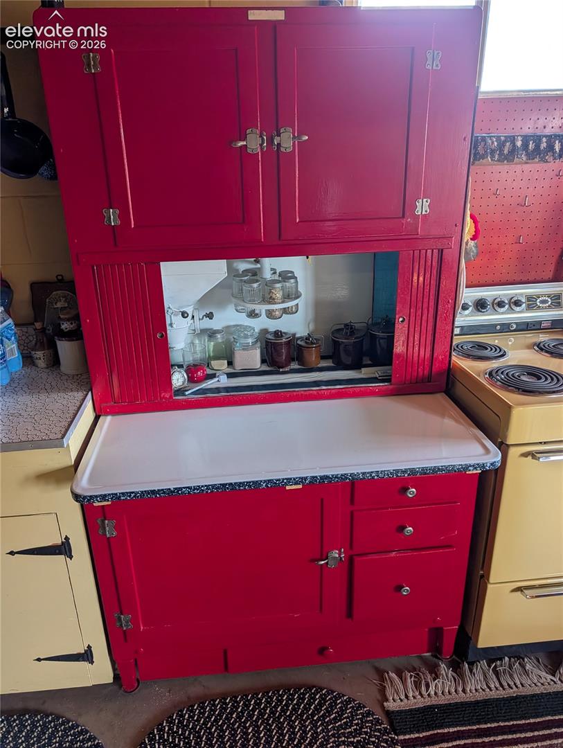 Freestanding red cabinetry with upper storage, a central open shelf, and lower drawers