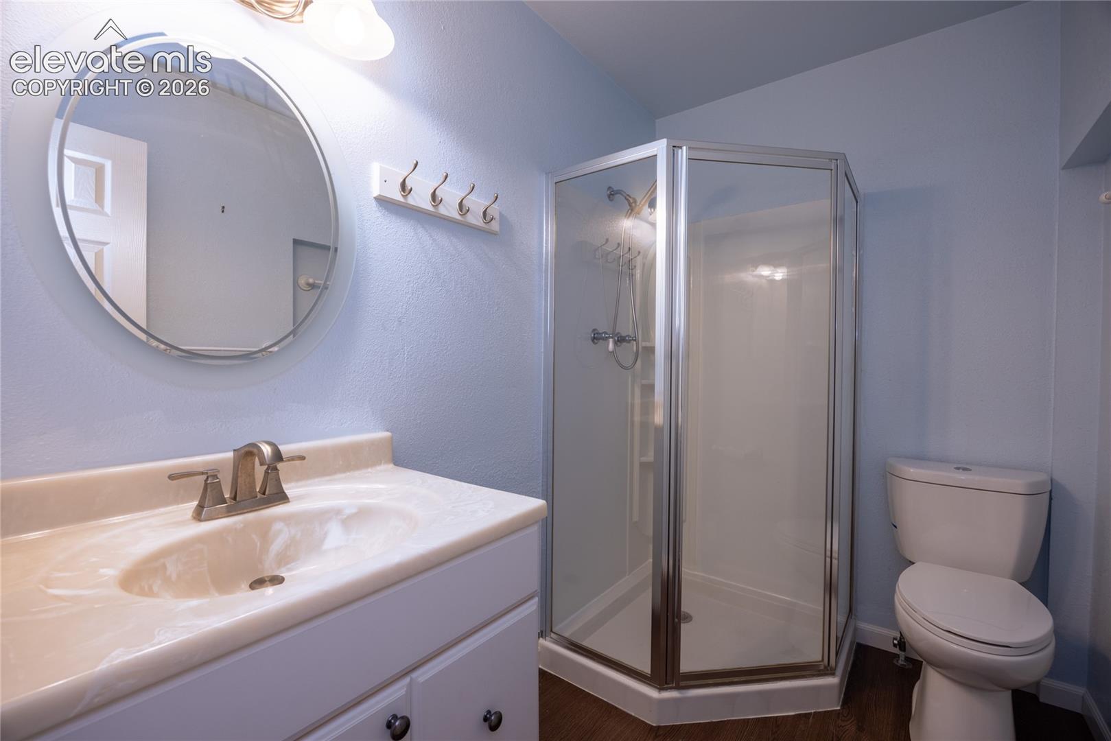 White vanity with integrated sink, brushed nickel faucet, and round mirror