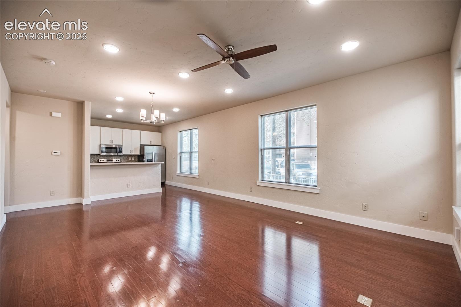 Open-concept living space featuring wood-finish flooring, recessed lighting, and a ceiling fan