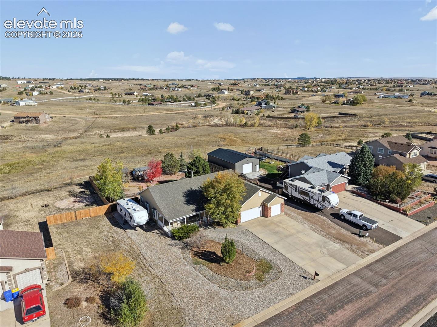 Single-story residence featuring an attached two-car garage, concrete driveway, detached metal workshop, and gravel landscaping