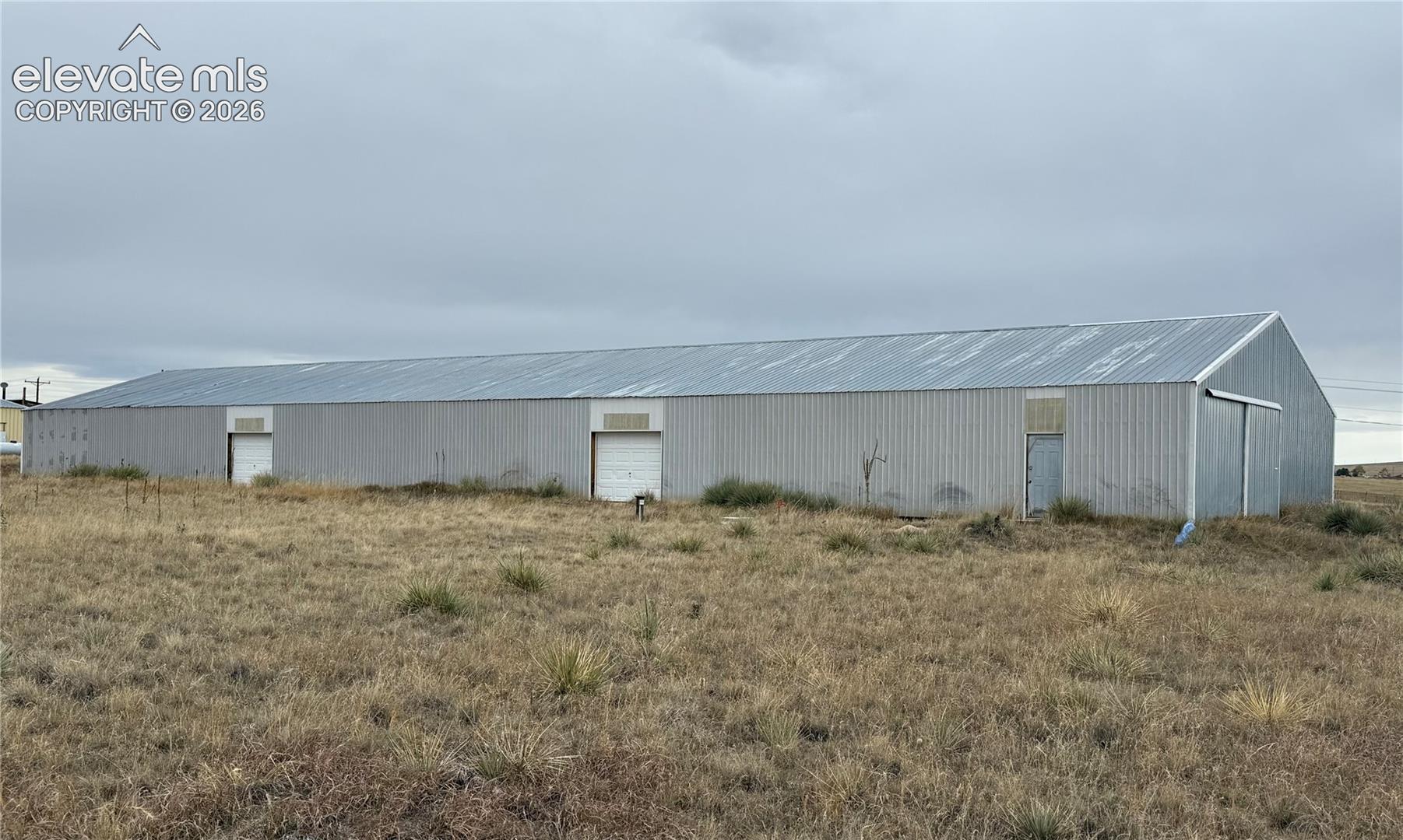 Large-format metal outbuilding featuring a corrugated steel exterior, a pitched metal roof, and multiple garage-style entry doors