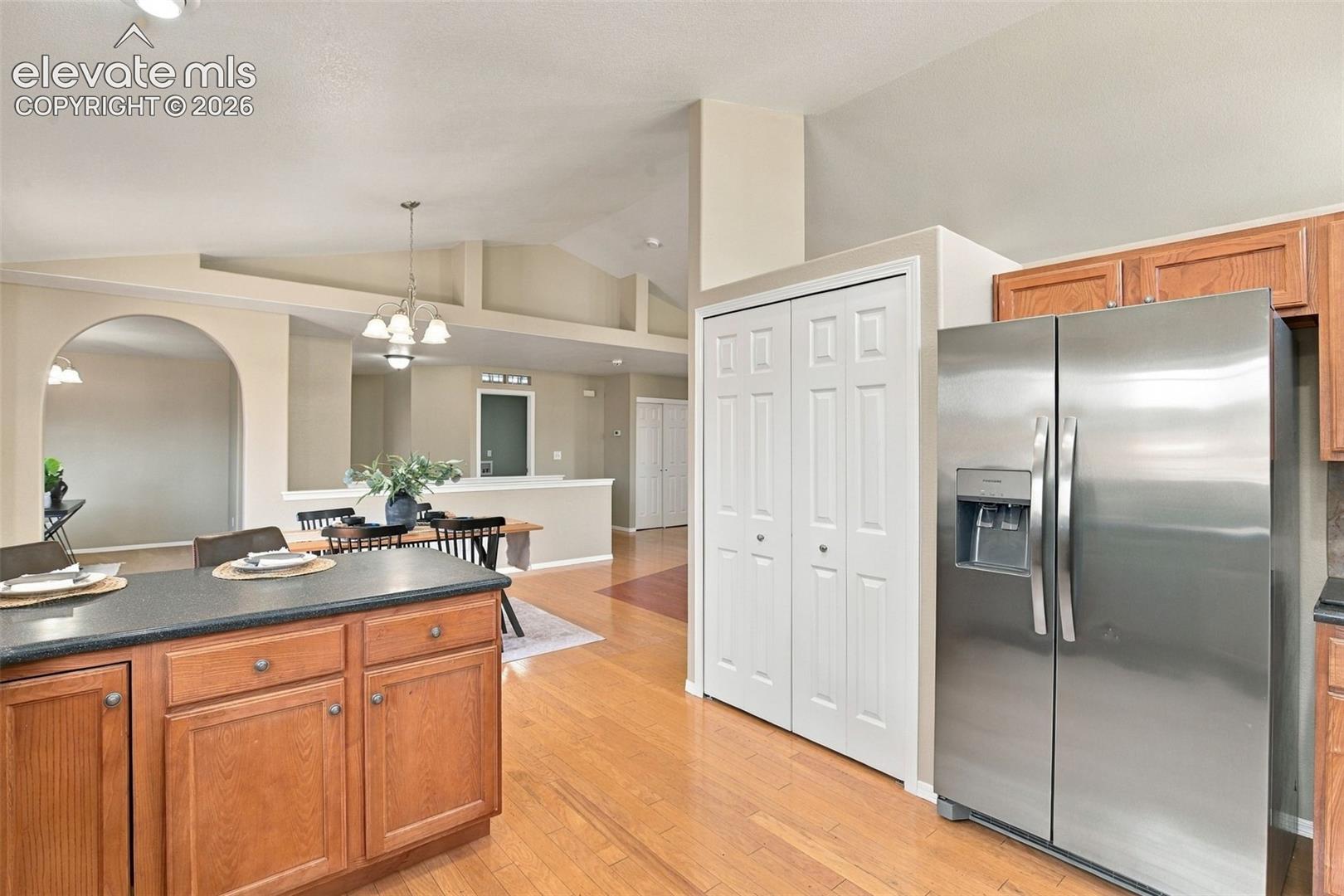 Kitchen featuring wood-finish flooring, a kitchen island with dark countertops, wood cabinetry, and stainless steel appliances