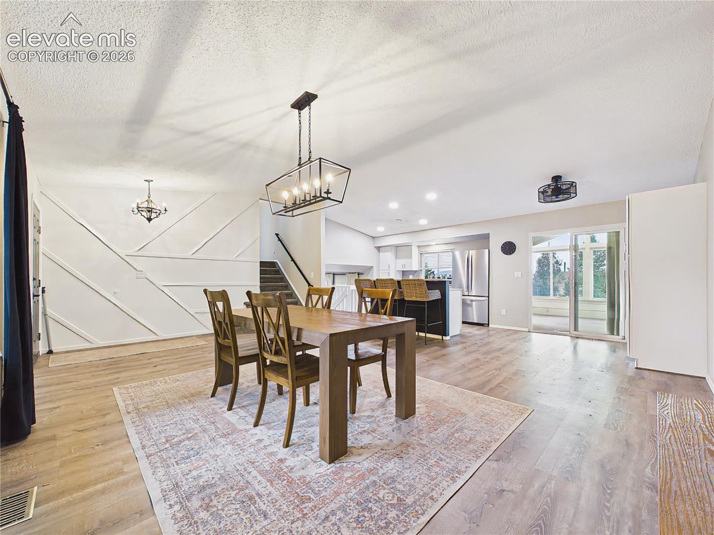 Spacious dining area with contemporary lighting, durable luxury vinyl plank flooring, and an open layout connecting to the kitchen and adjacent living spaces.