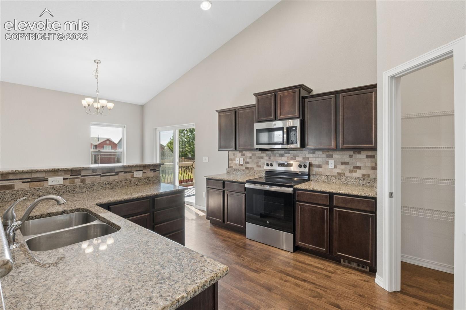 Kitchen featuring wood-finish flooring, dark wood cabinetry, and speckled countertops