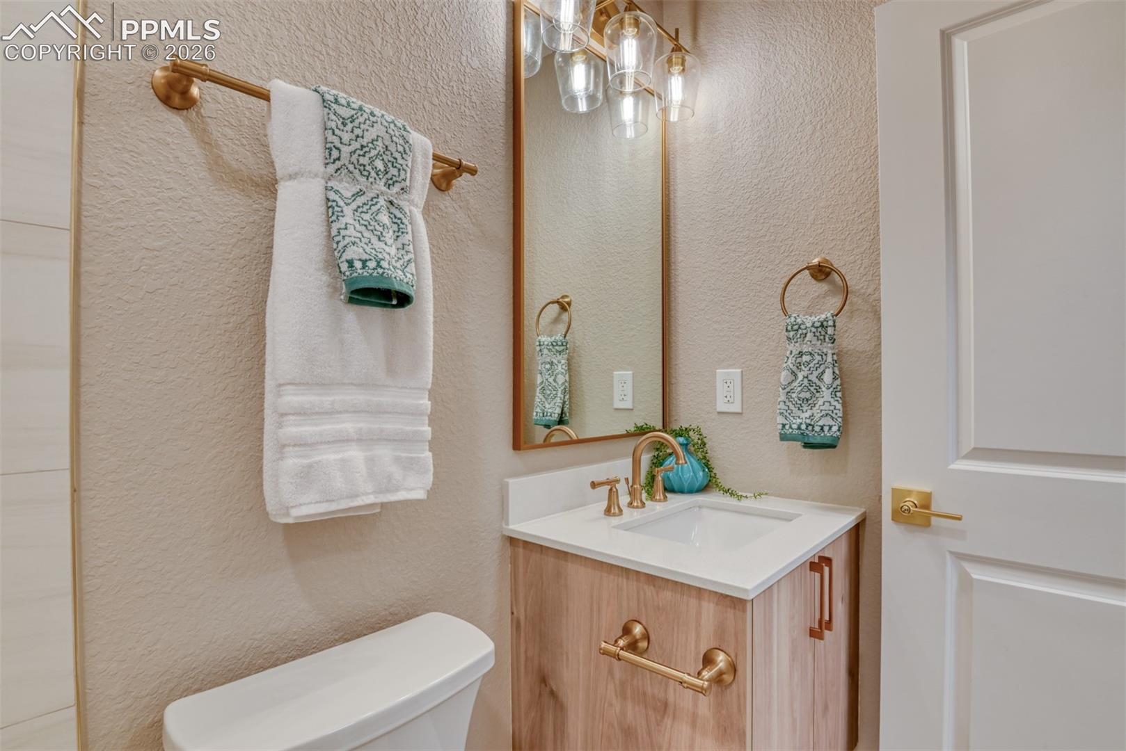 Half bath featuring vanity and a textured wall