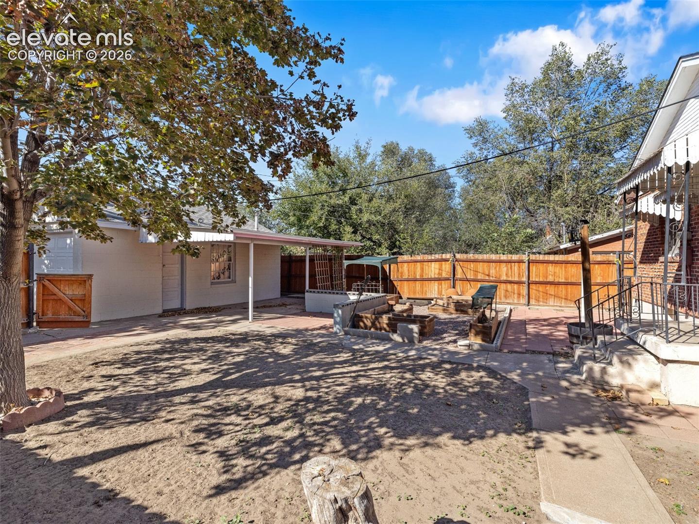 Backyard featuring a paved patio, perimeter wood fencing, built-in masonry planters, and a detached covered structure