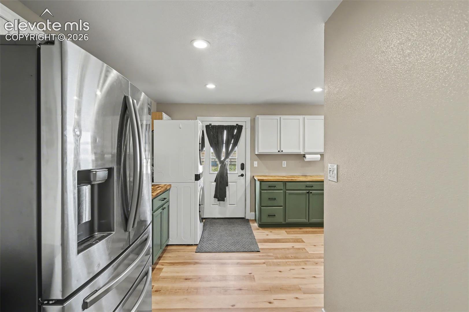 Stainless steel French door refrigerator, wood-finish flooring, dual-tone cabinetry, and butcher block countertops