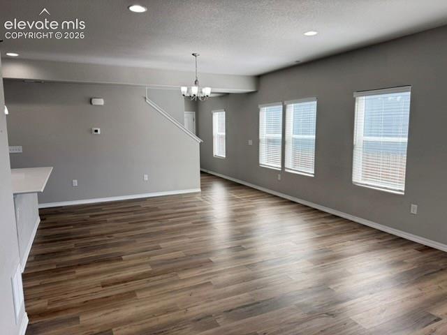 Open concept living space featuring wood-finish flooring, multiple windows with blinds, recessed lighting, and a contemporary chandelier