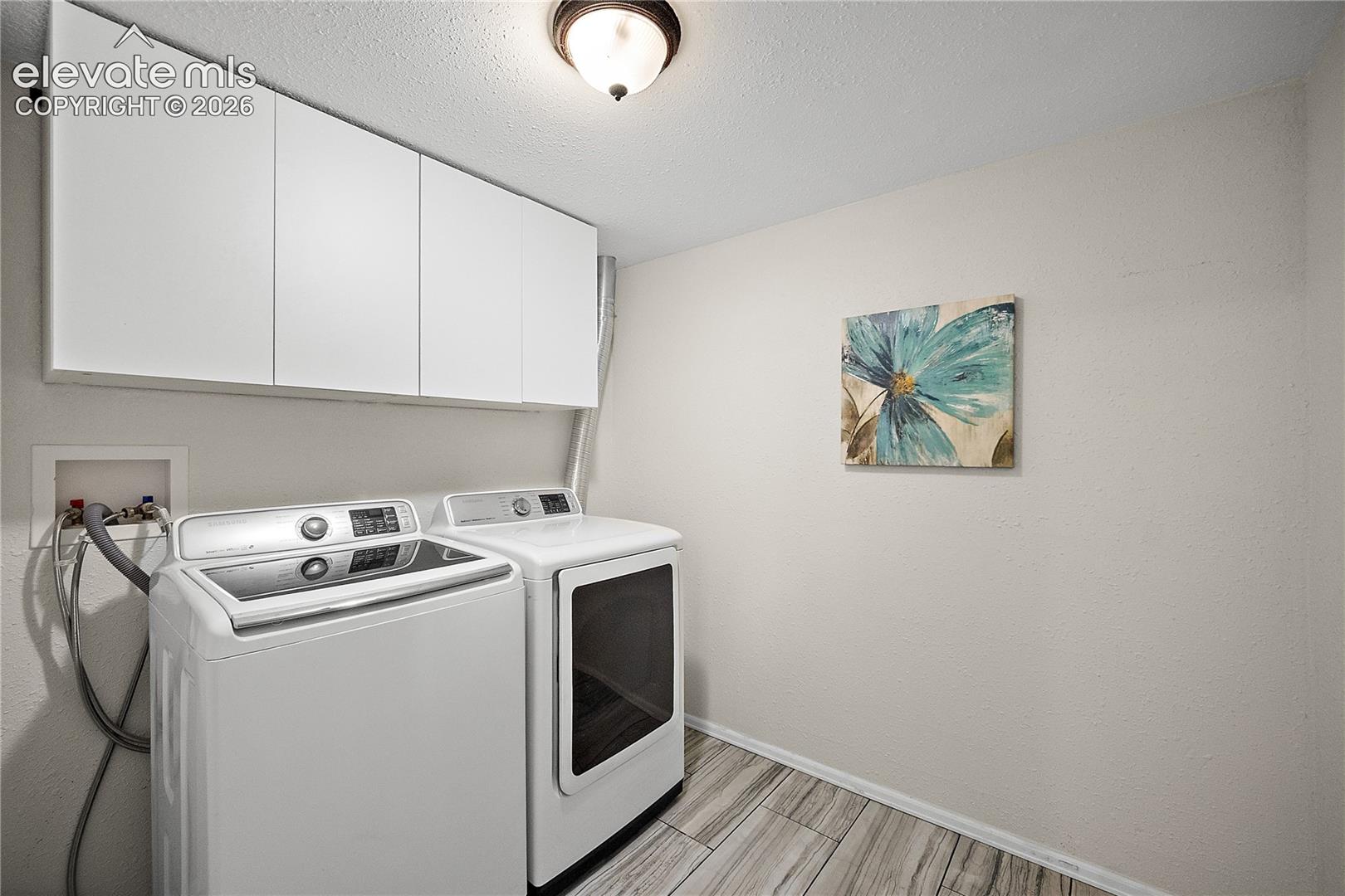 Laundry area featuring white cabinetry, wood-finish flooring, a neutral wall color, and overhead lighting