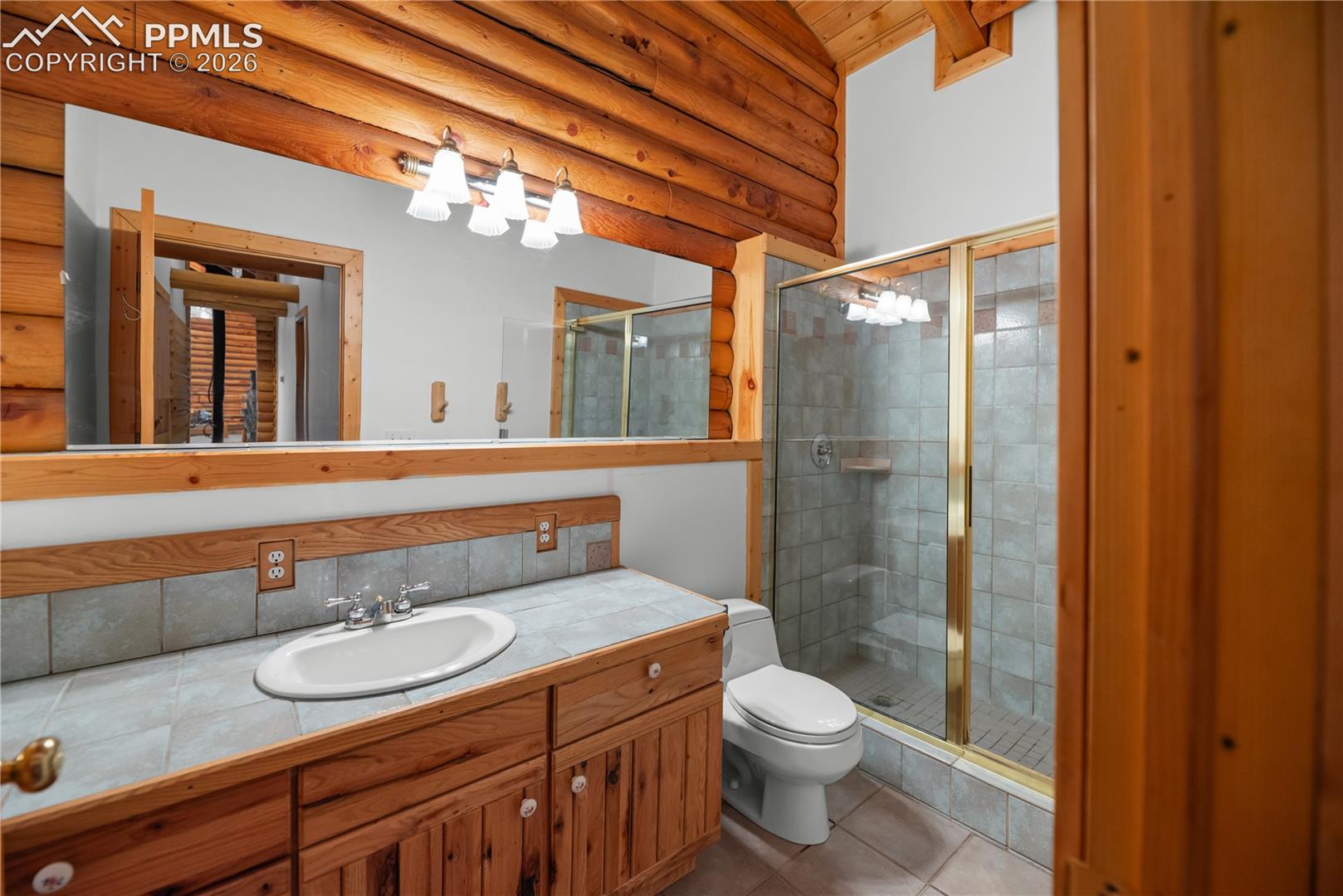 Bathroom with log walls, vanity, a stall shower, tile patterned floors, and beamed ceiling