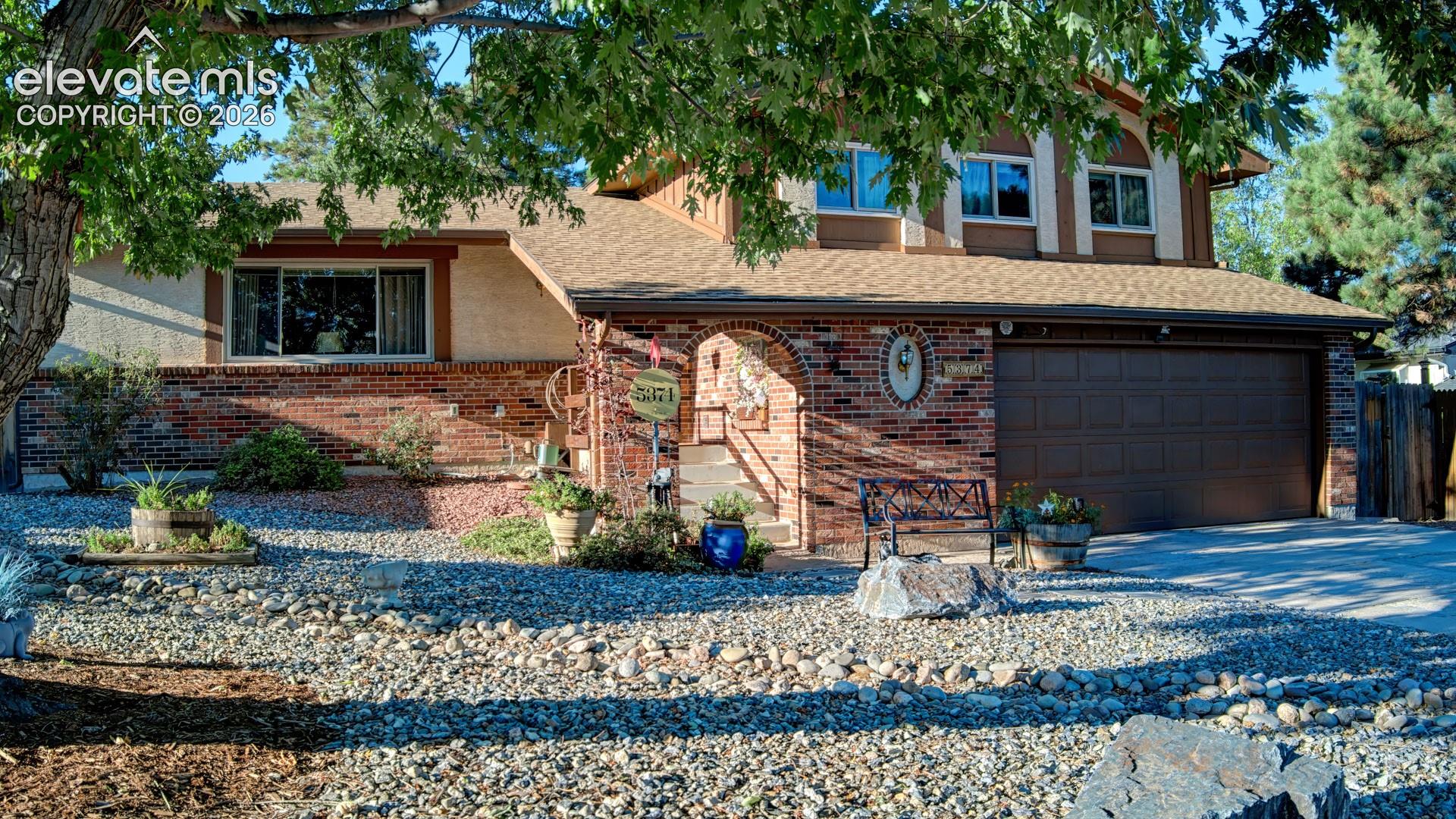 Brick facade with arched entry, attached two-car garage, and upper-level windows