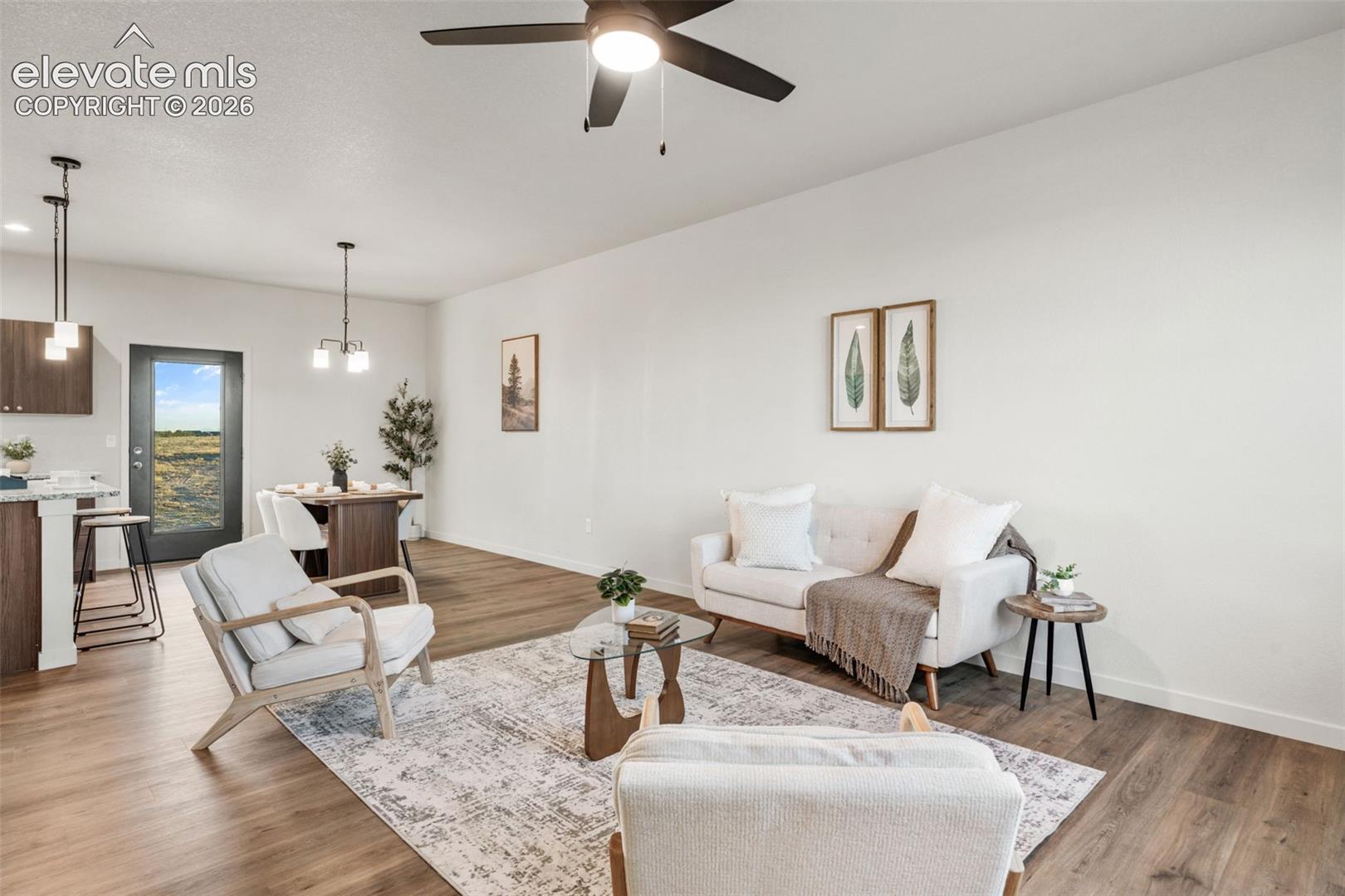 Open-concept floor plan featuring wood-finish flooring, recessed lighting, multi-bulb pendant fixtures, a ceiling fan, and large windows