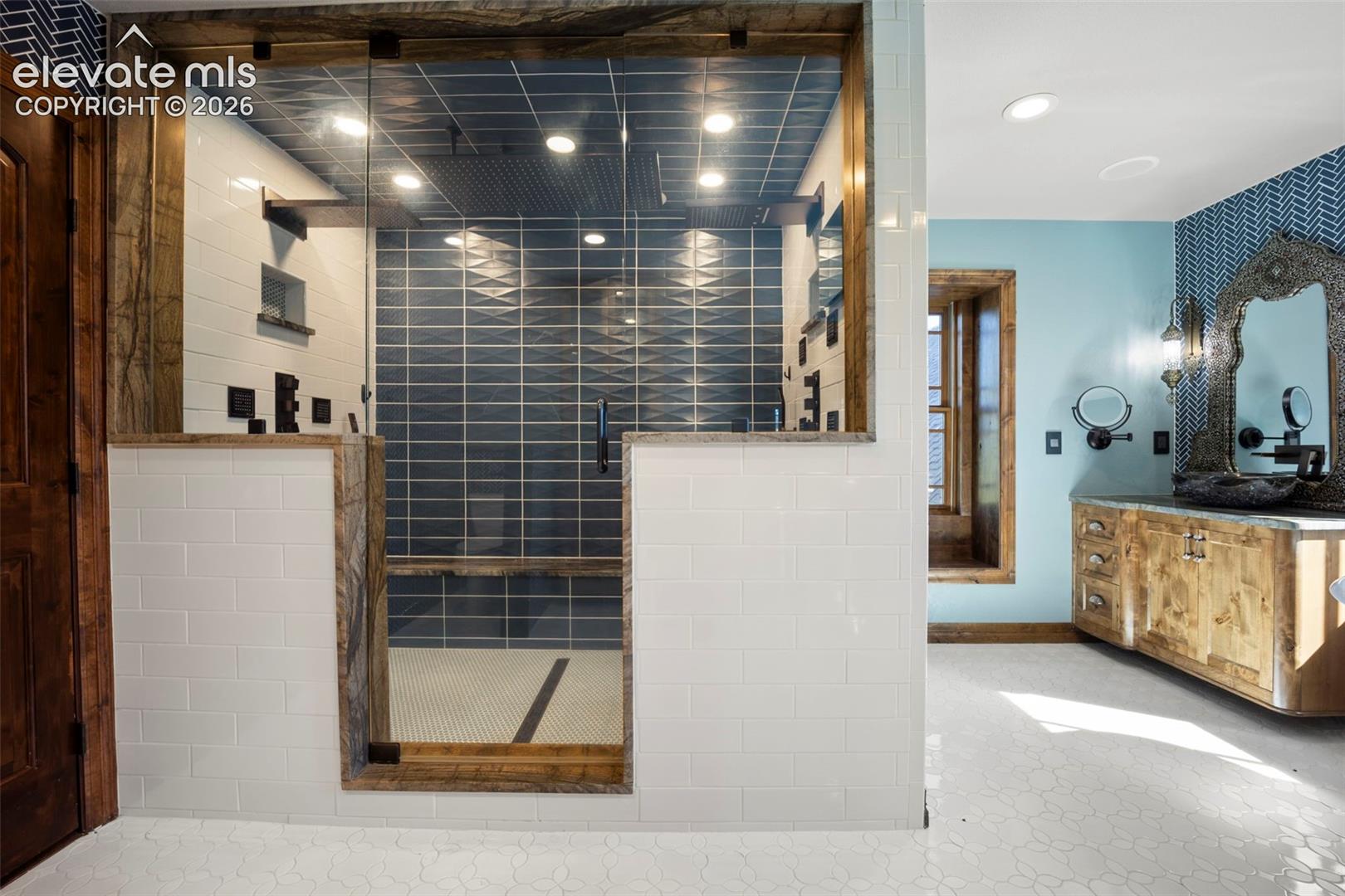 Walk-in shower featuring glass enclosure, large format blue tile, white subway tile surround, and recessed lighting