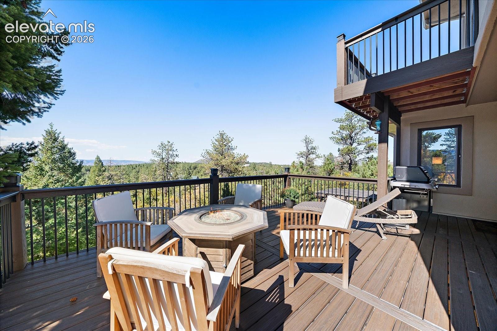 Spacious elevated deck featuring composite decking, metal railings, and a built-in balcony level above