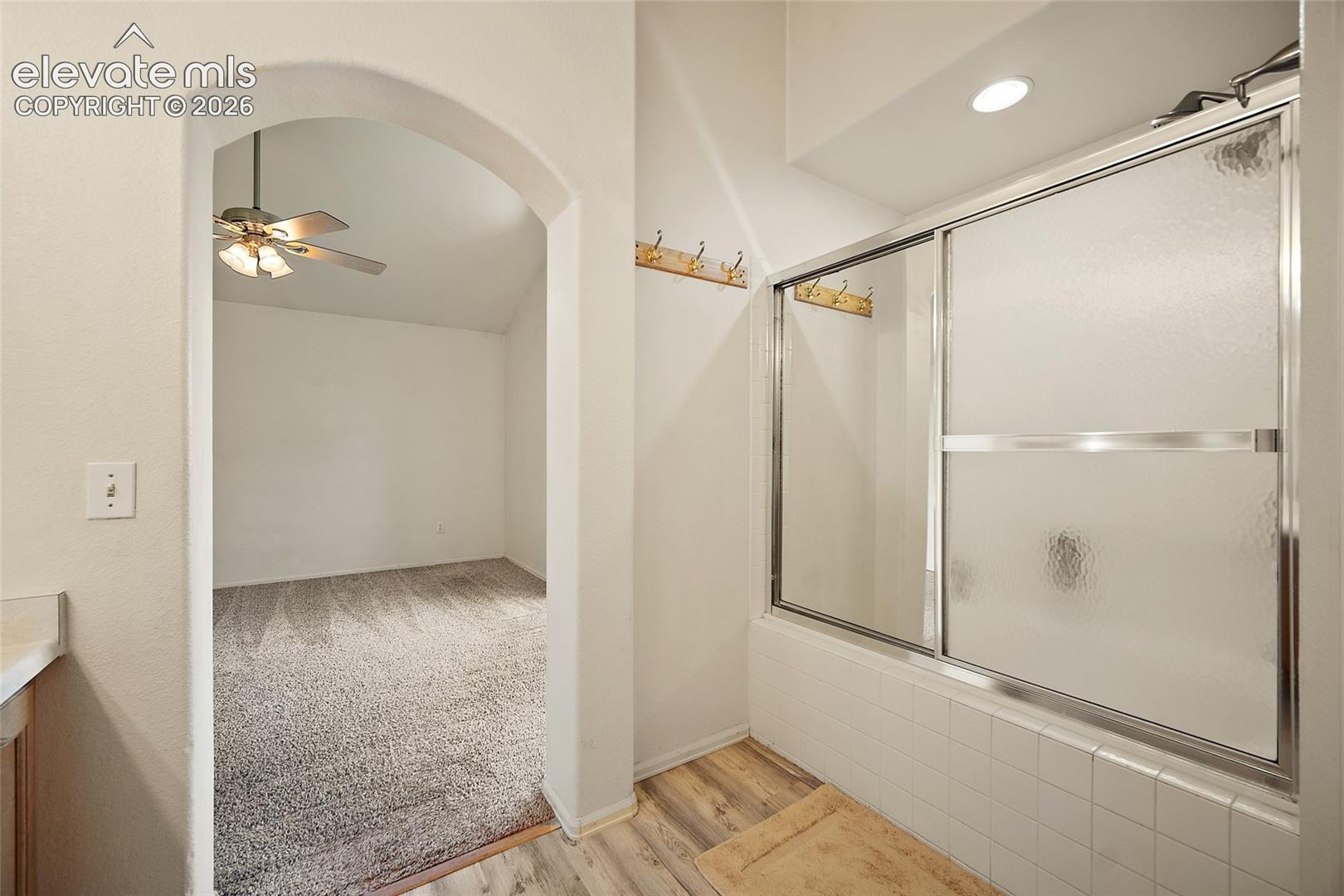 Bathroom with a white tiled shower/tub combination featuring a sliding glass door