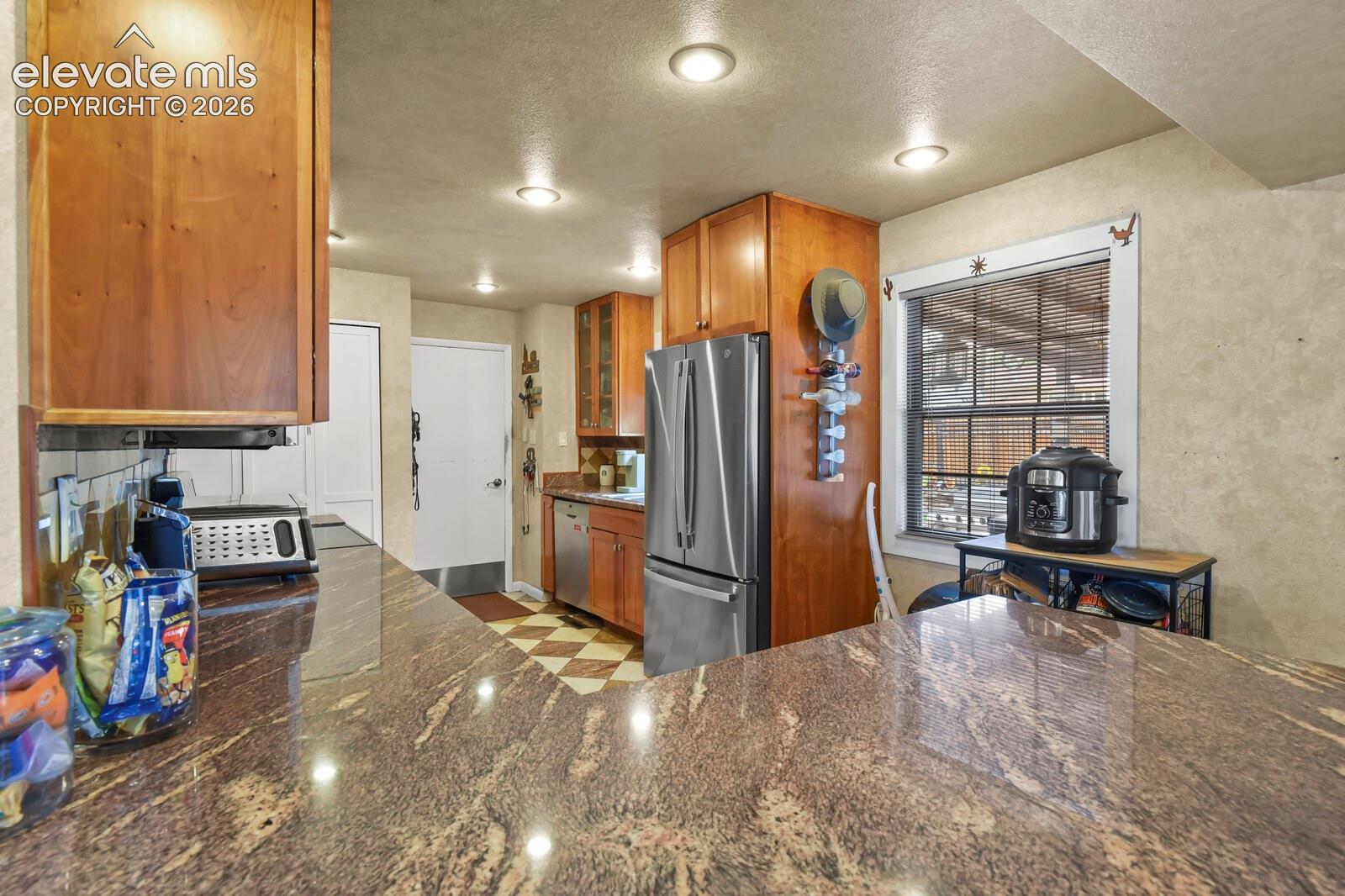 Kitchen featuring a stone-look countertop, wood cabinetry, recessed lighting, and stainless steel appliances