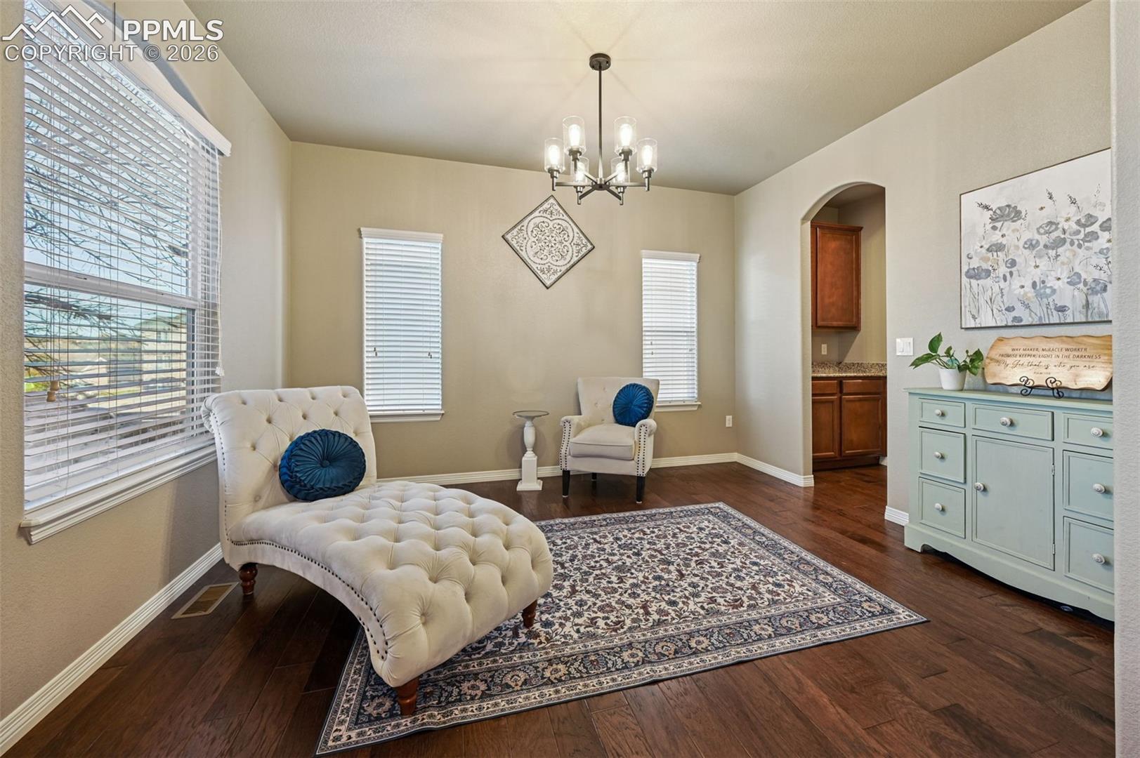 Living area featuring arched walkways, dark wood-style flooring, and hanging lights