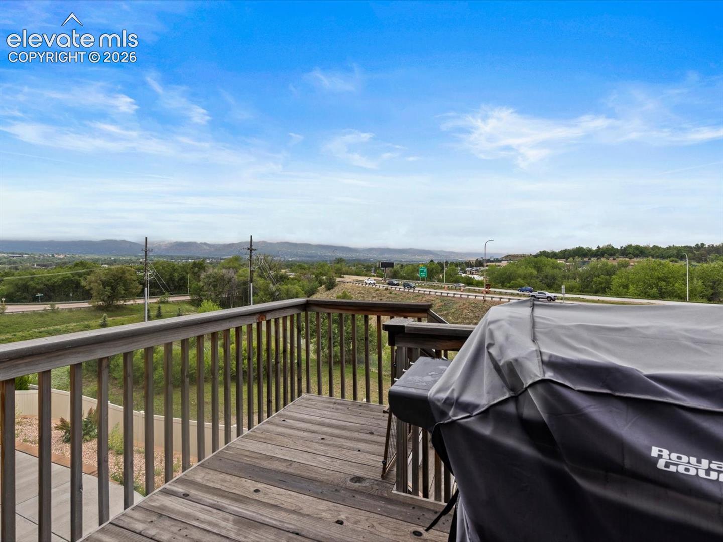 Spacious outdoor deck featuring natural wood flooring and a sturdy wood railing