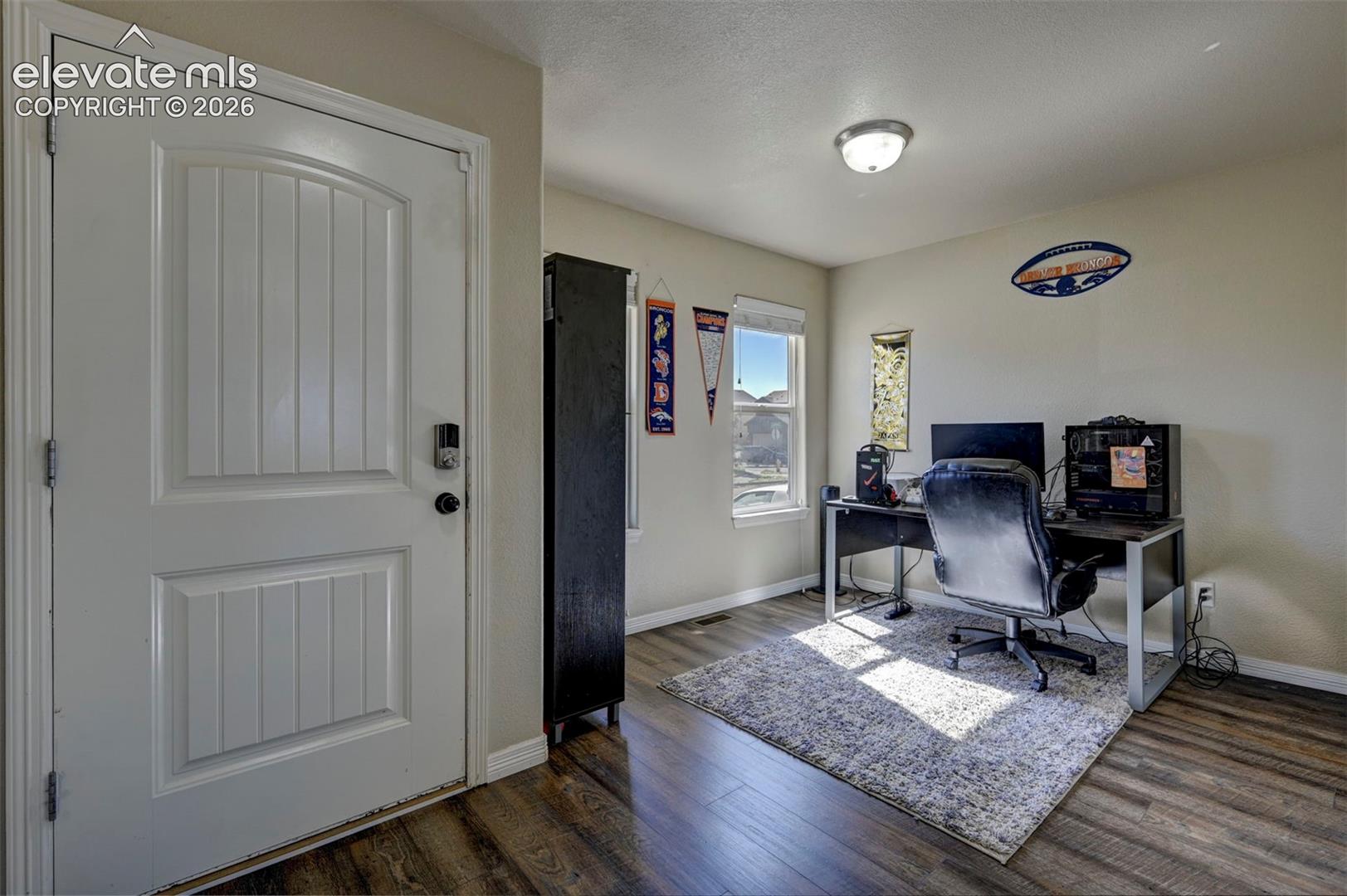 White paneled entry door with smart lock, wood-finish flooring, and two windows
