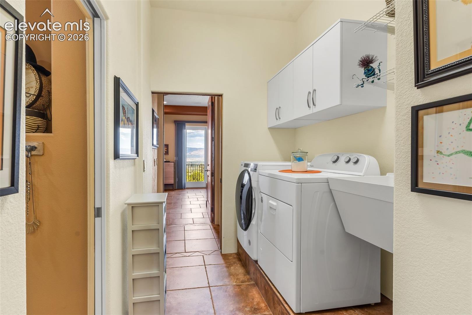 Laundry room featuring tile flooring, white built-in upper cabinetry, and a dedicated utility sink