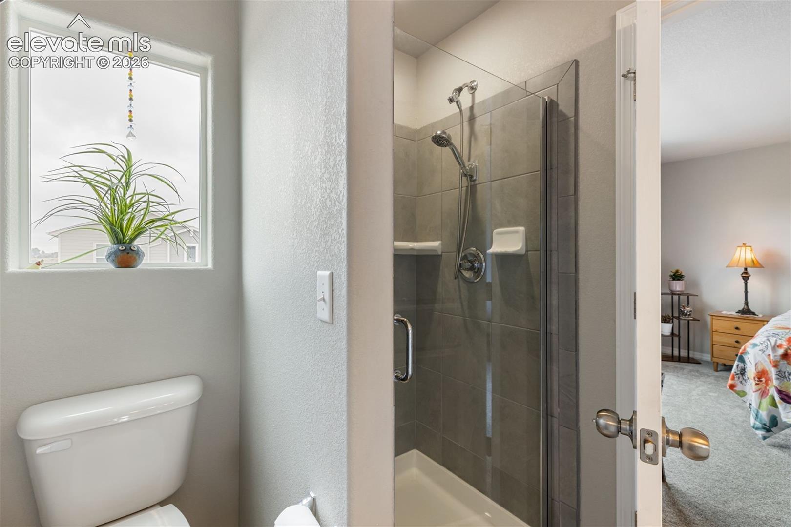 Bathroom featuring a walk-in shower with glass enclosure, gray tile surround, and chrome fixtures