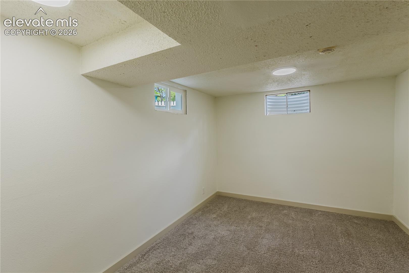 4th bedroom - Carpeted room featuring two egress windows with horizontal blinds, recessed lighting, and a textured ceiling