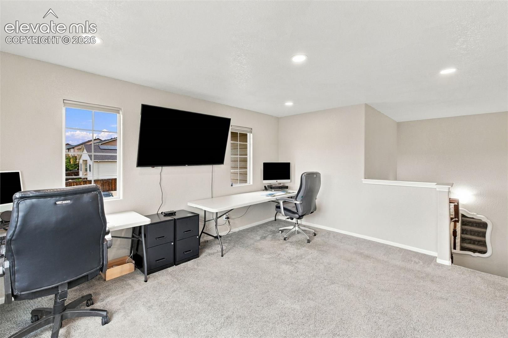 Neutral-toned interior space featuring recessed ceiling lighting, wall-to-wall carpeting, and multiple windows providing natural illumination