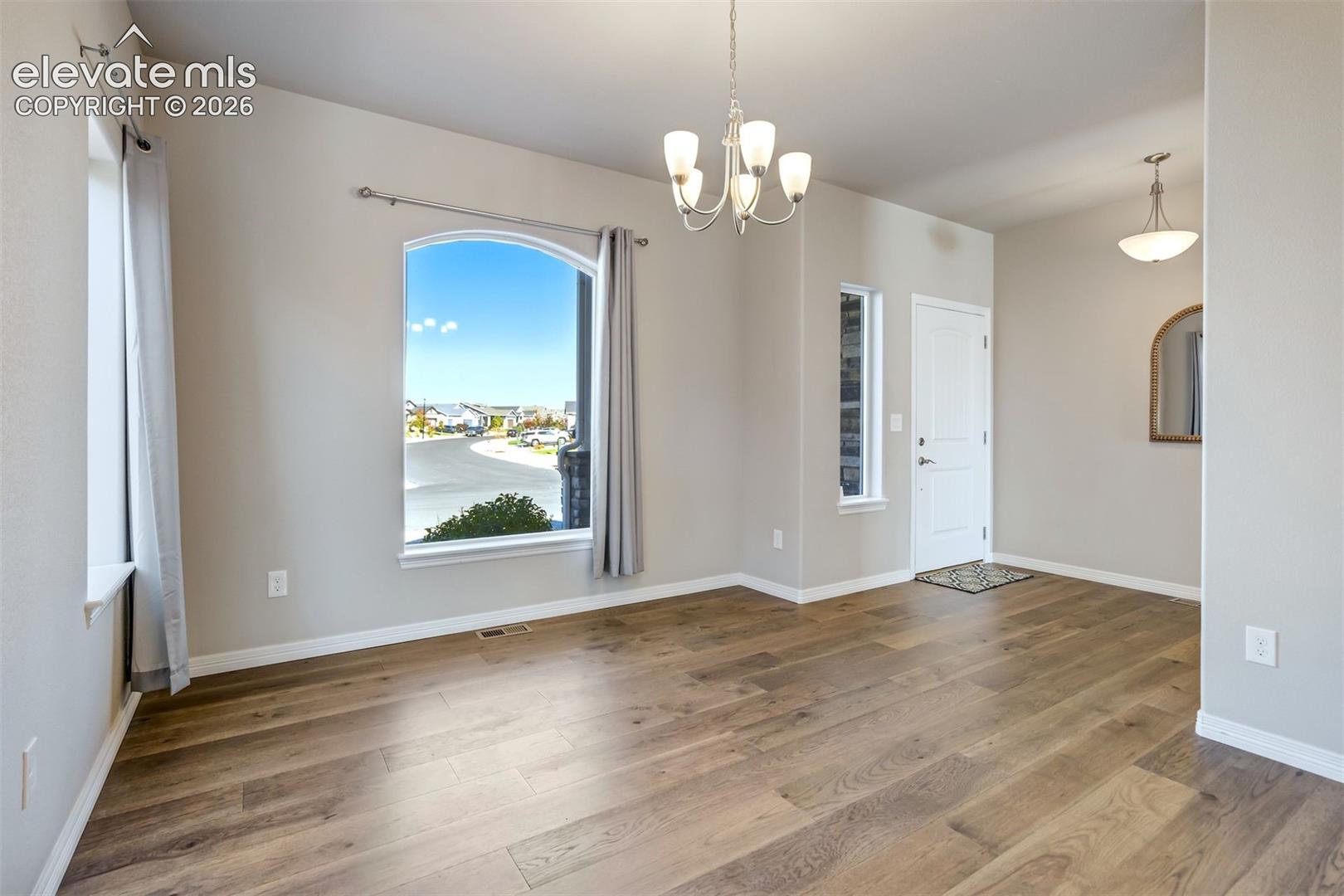 Arched window, wood-finish flooring, white trim, recessed lighting, and a chandelier