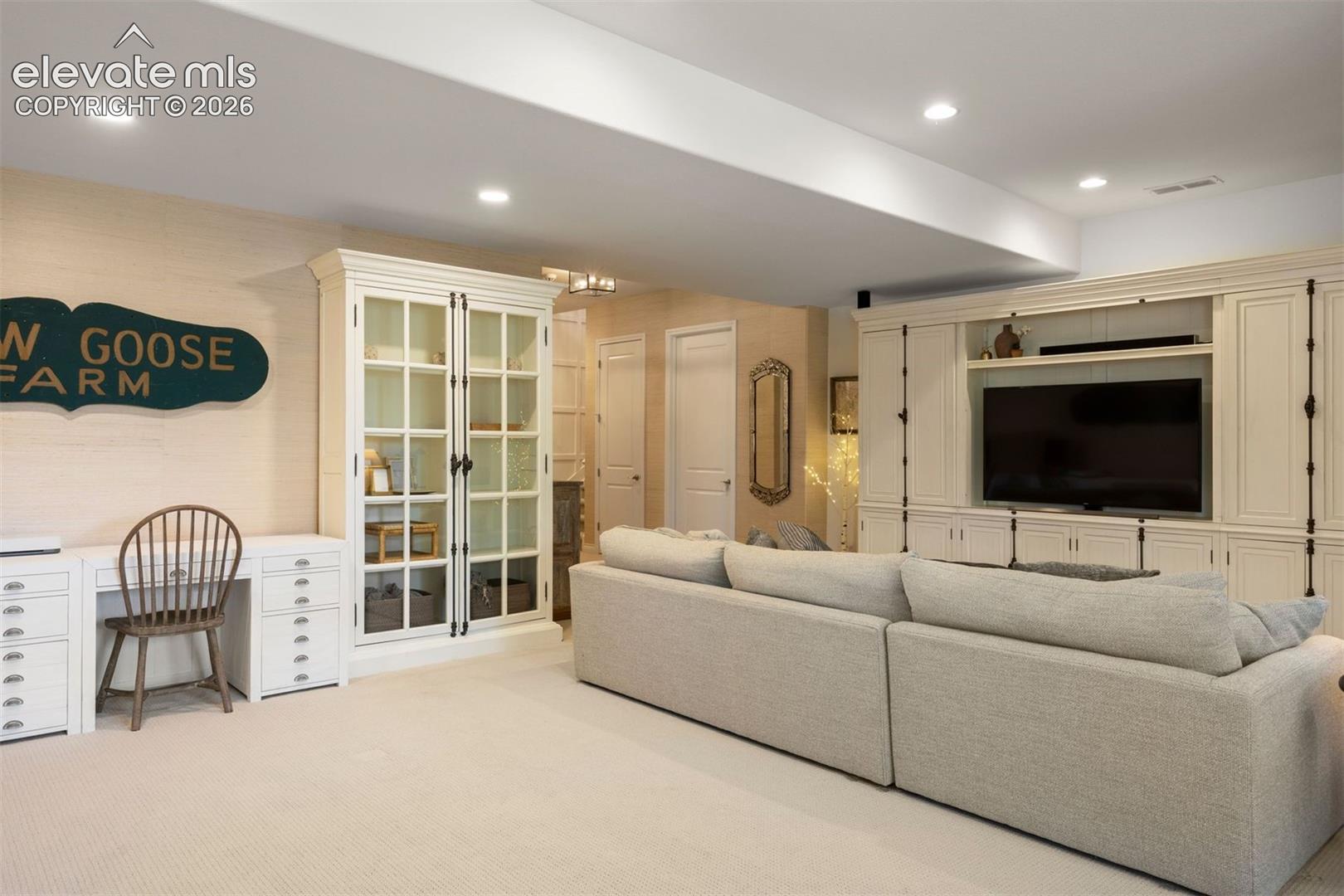 Integrated entertainment center with custom cabinetry, recessed lighting, built-in desk area, and neutral carpeting