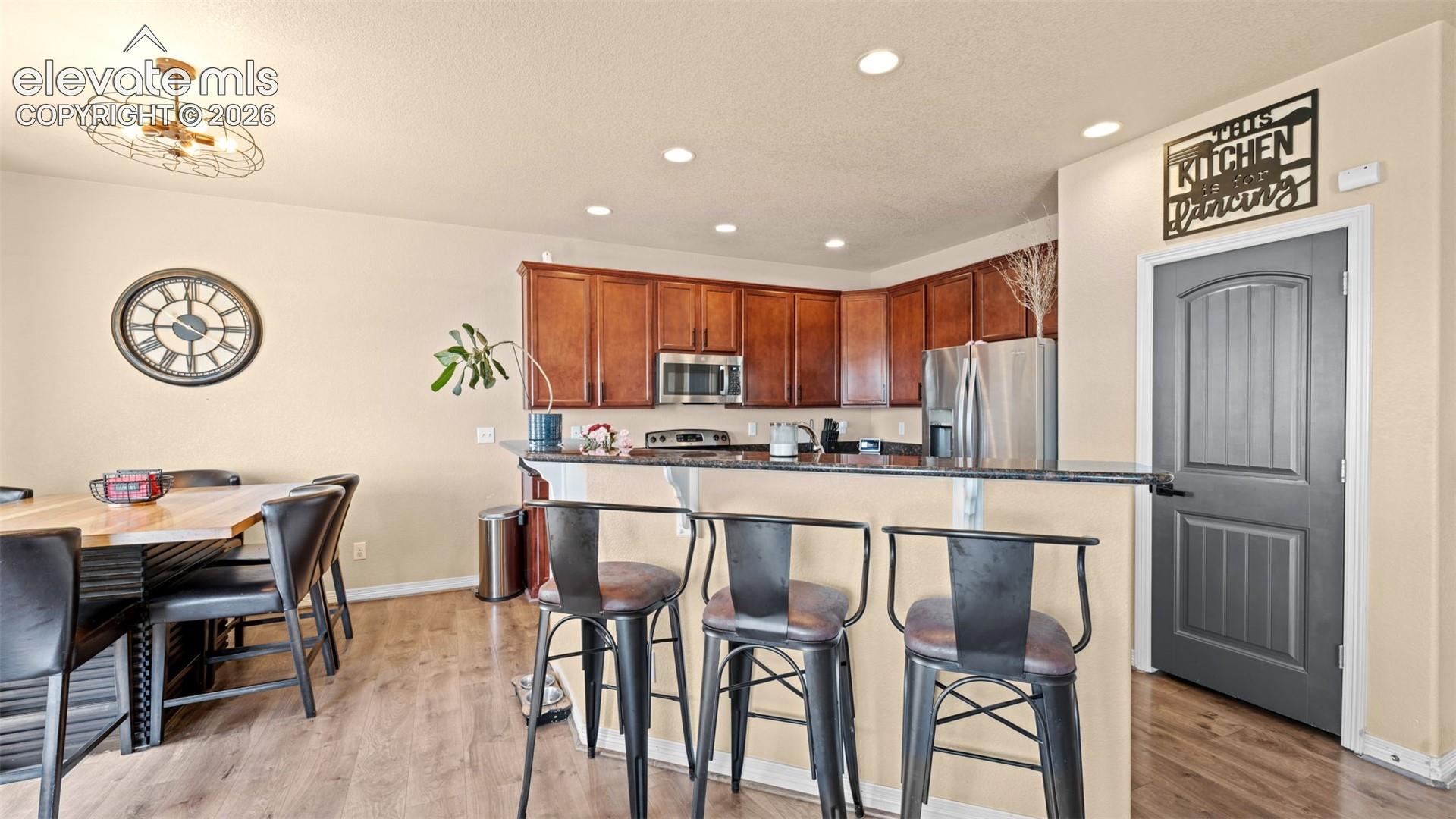 Kitchen featuring wood-finish flooring, recessed lighting, and a breakfast bar with 42 inch countertops