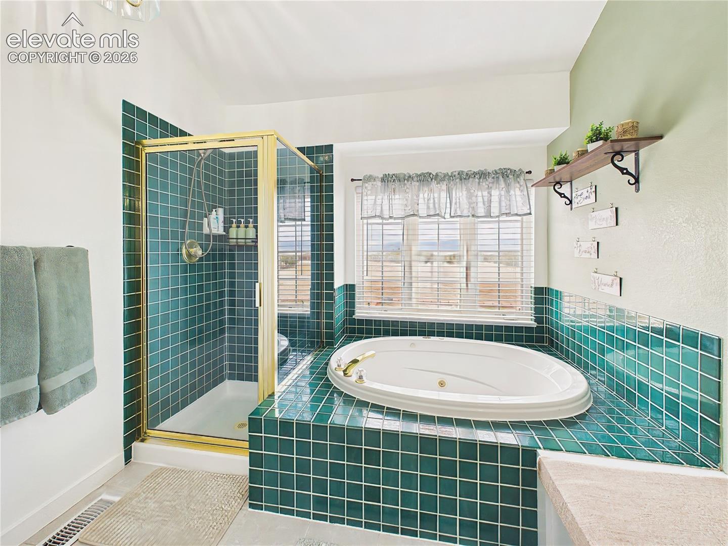 Spa-inspired bath includes a soaking jetted tub, separate shower, and large windows showcasing the surrounding landscape.