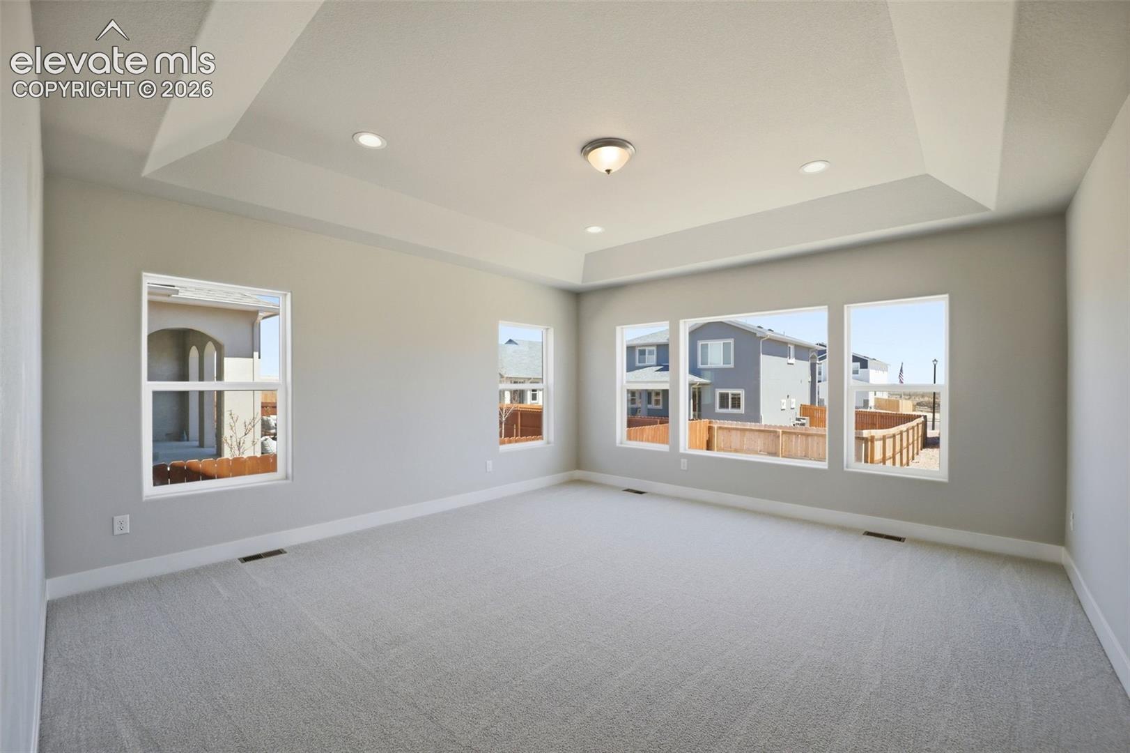 Tray ceiling featuring recessed lighting and multiple windows providing natural illumination