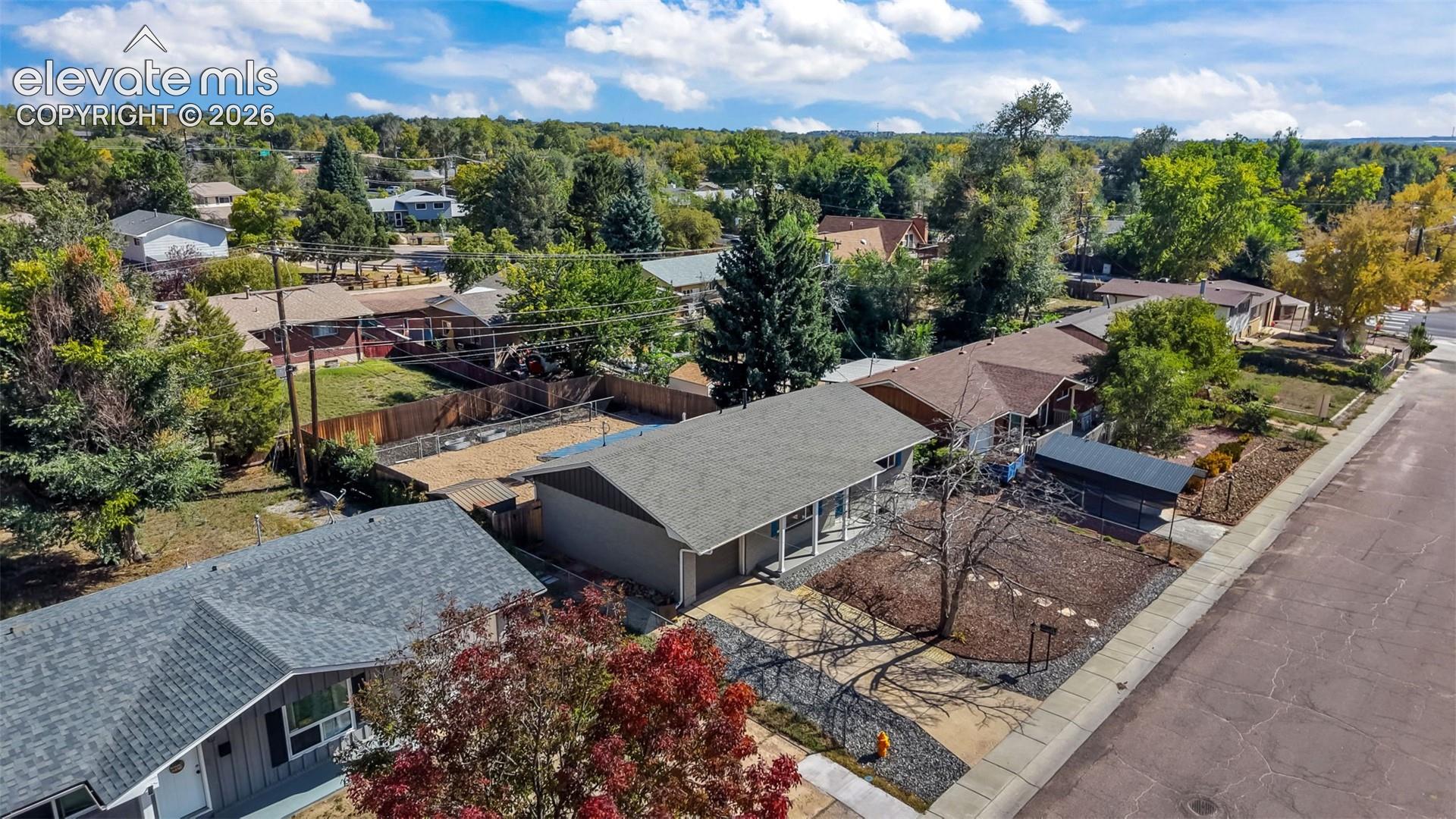 Aerial perspective showcasing multiple properties with varied rooflines and a mix of deciduous and evergreen trees