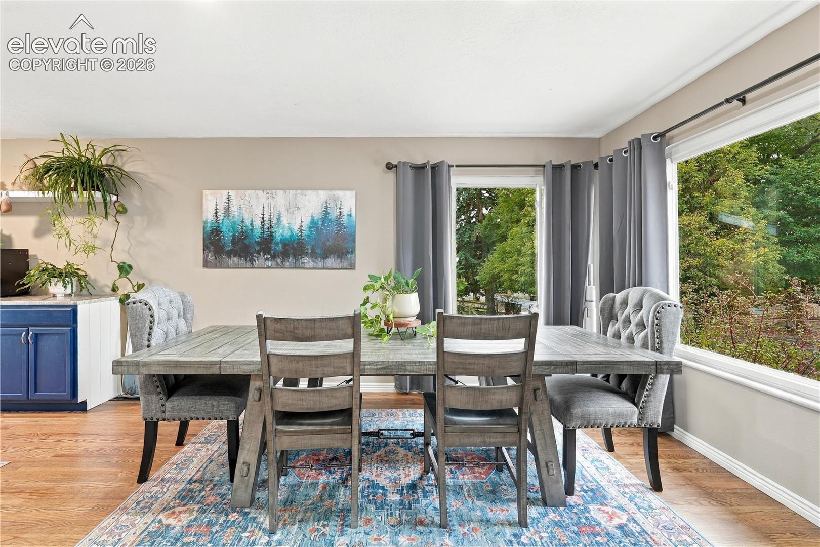 Dining area featuring wood-finish flooring, a large picture window, and glass-panel door access to the exterior