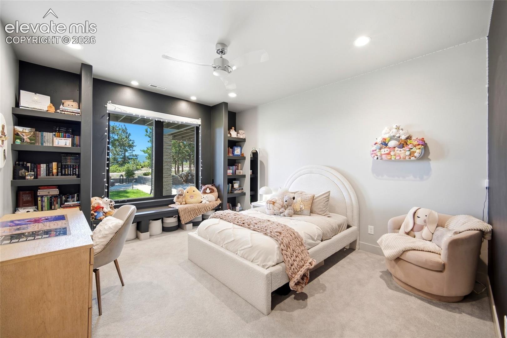 Built-in shelving, expansive window, recessed lighting, ceiling fan, and light-toned carpet