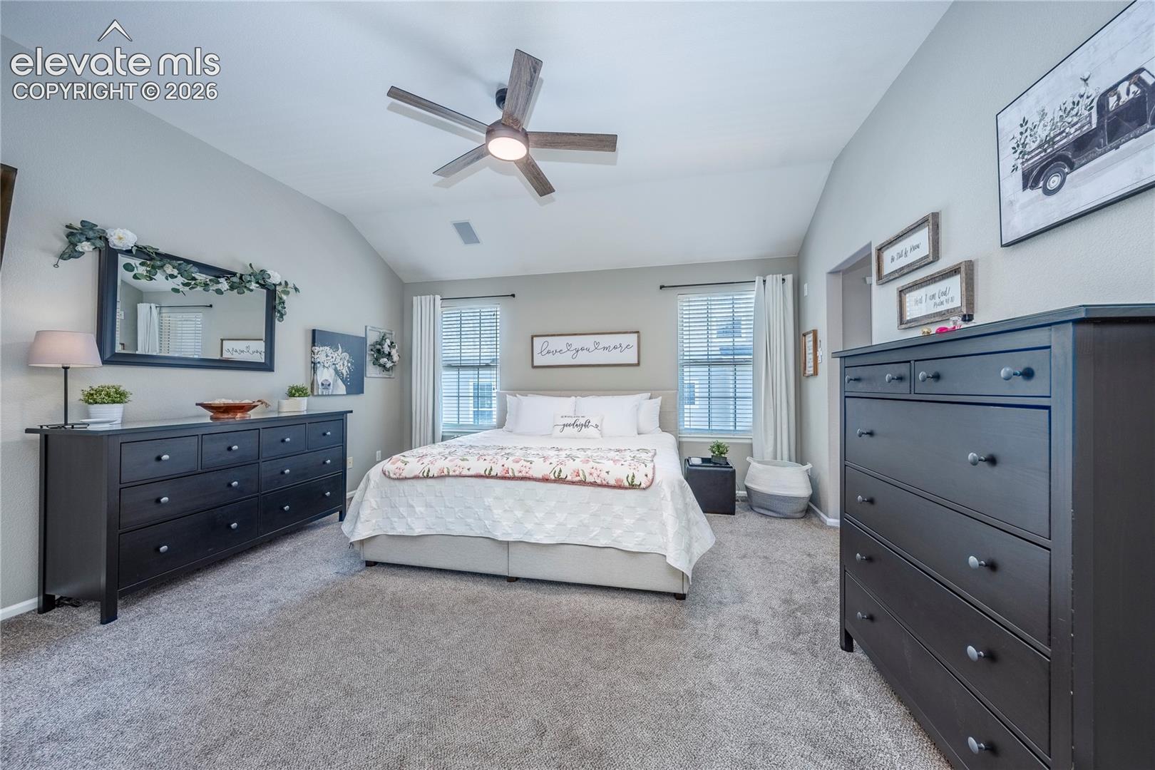 Vaulted ceilings, carpeted flooring, and a multi-blade ceiling fan with integrated lighting