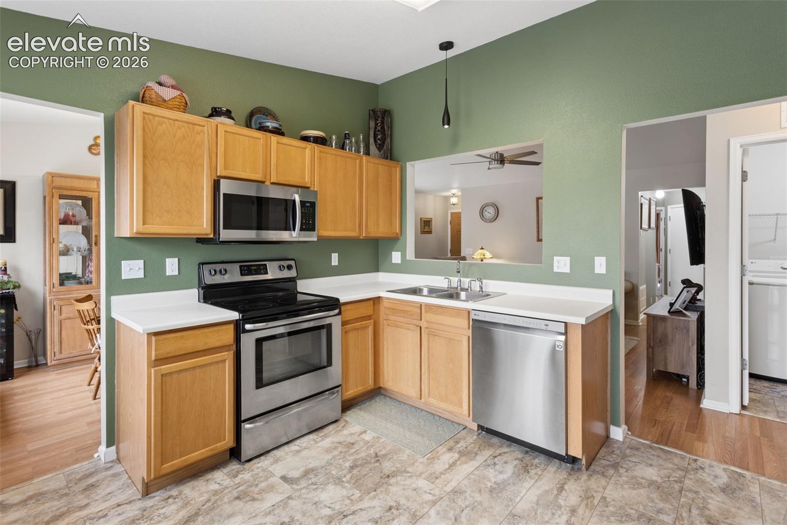 Kitchen featuring wood-finish cabinetry, stainless steel appliances, white countertops, and a pass-through window