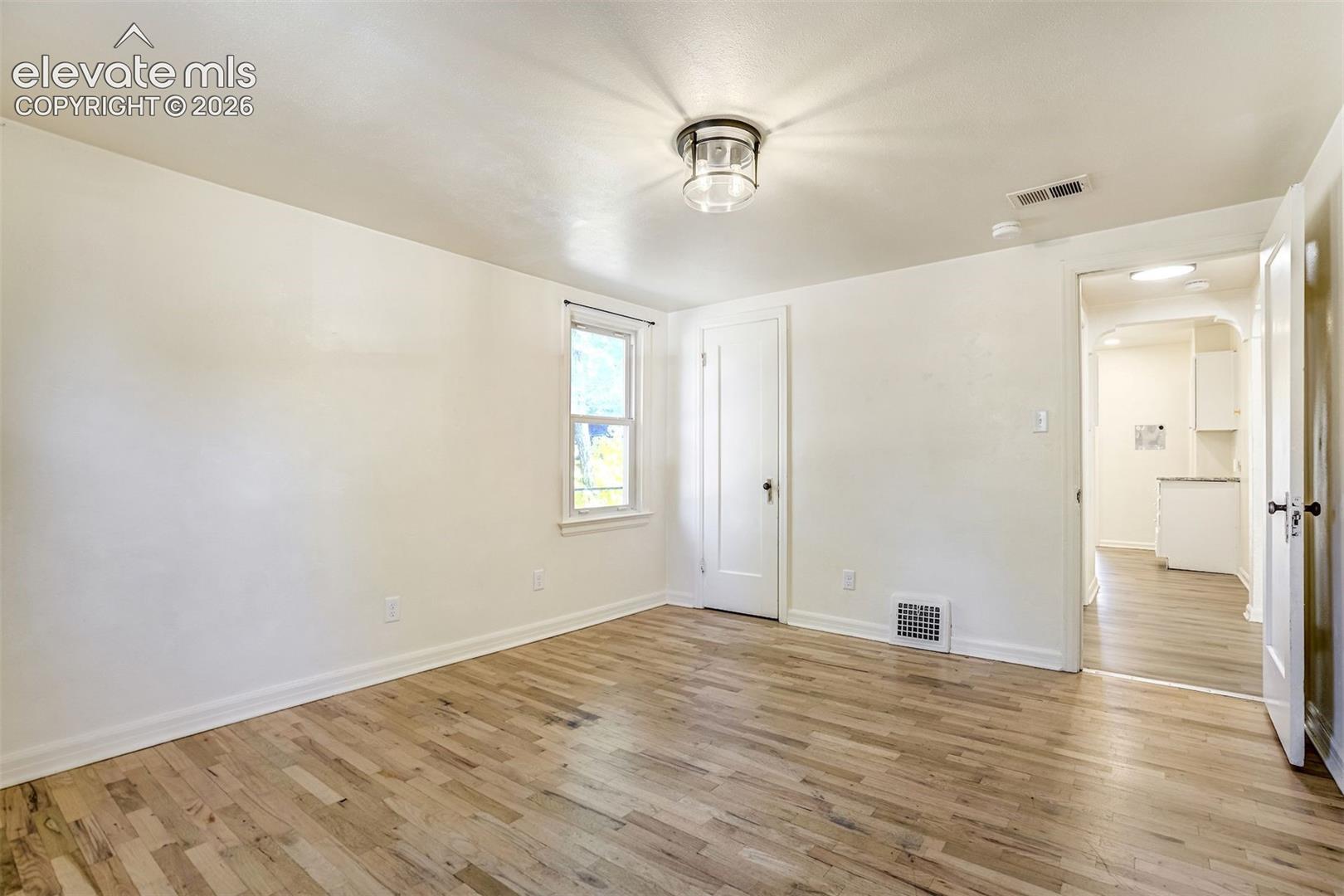 Neutral-toned interior featuring wood-finish flooring, a flush-mount circular light fixture, and a single-pane window