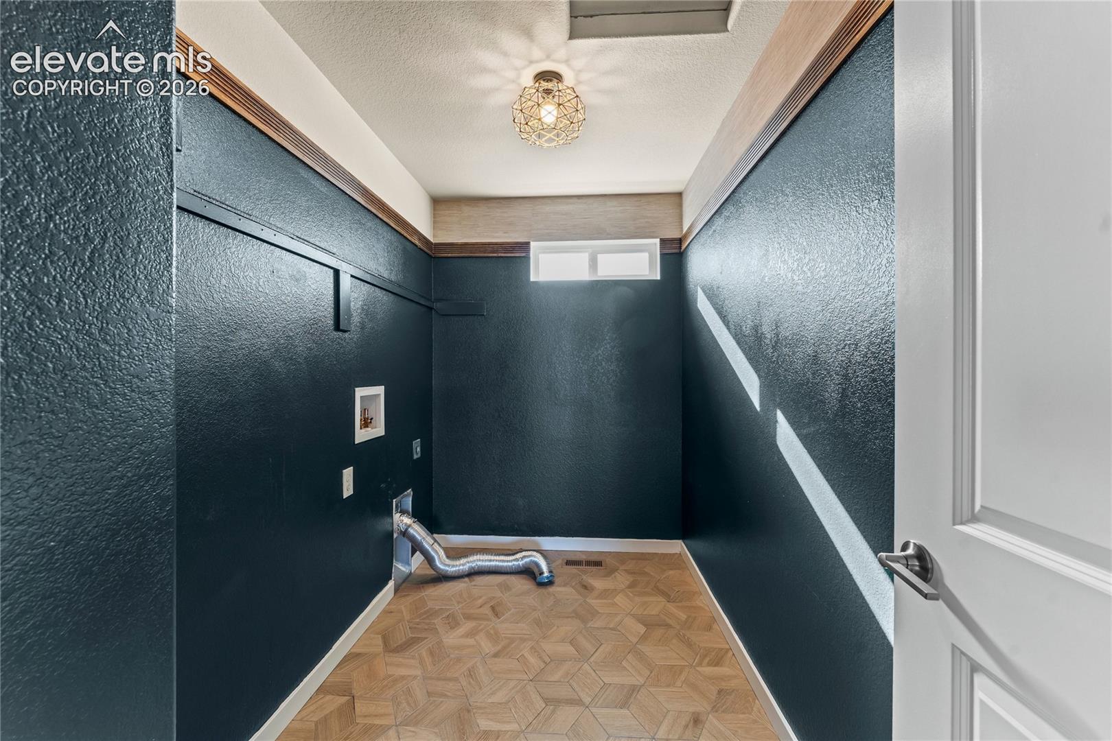 Geometric patterned flooring, dark accent walls with horizontal trim detailing, natural wood-tone ceiling border, and a decorative orb-style light fixture