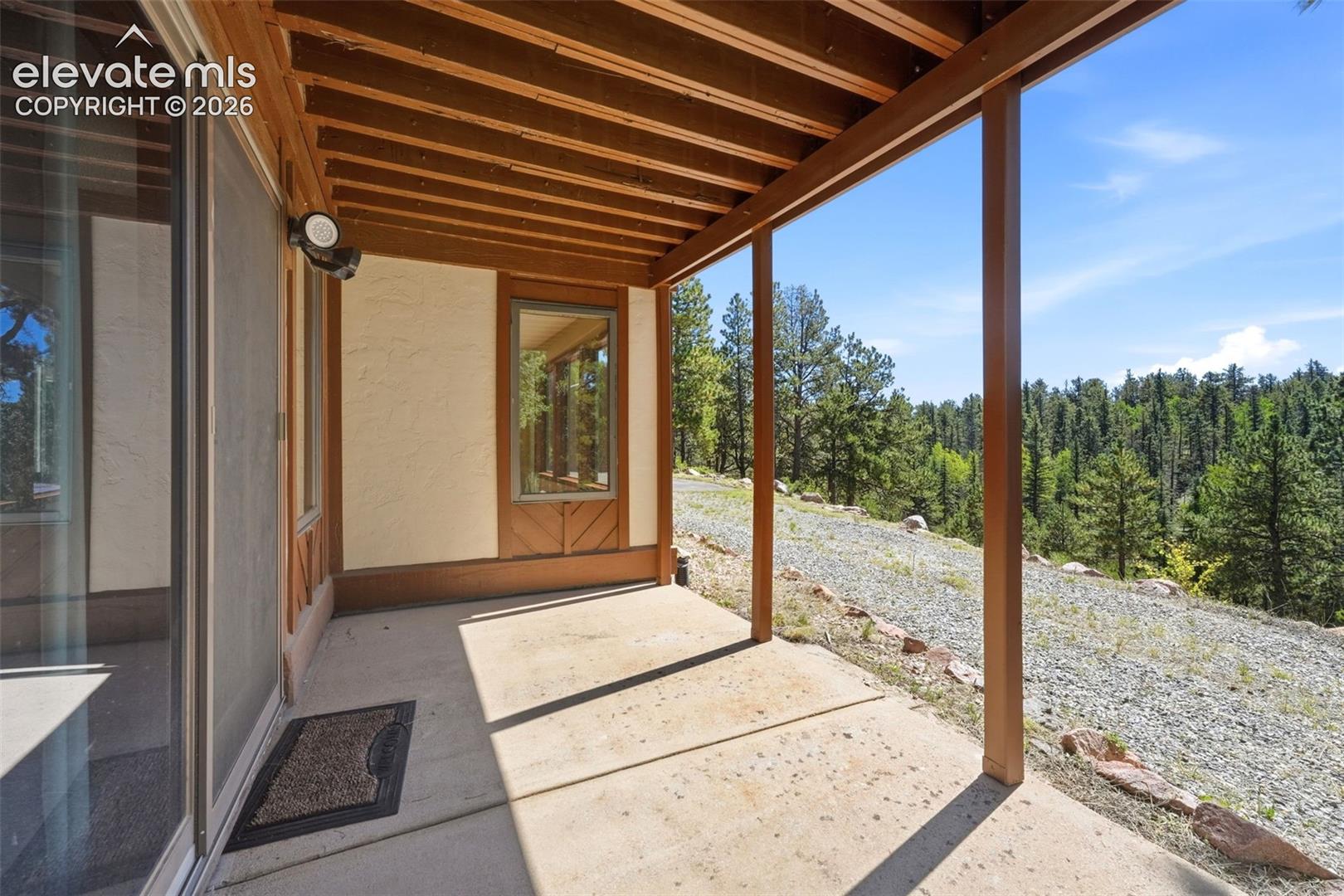 Covered patio with a concrete surface, exposed wood beam ceiling, and sliding glass door access