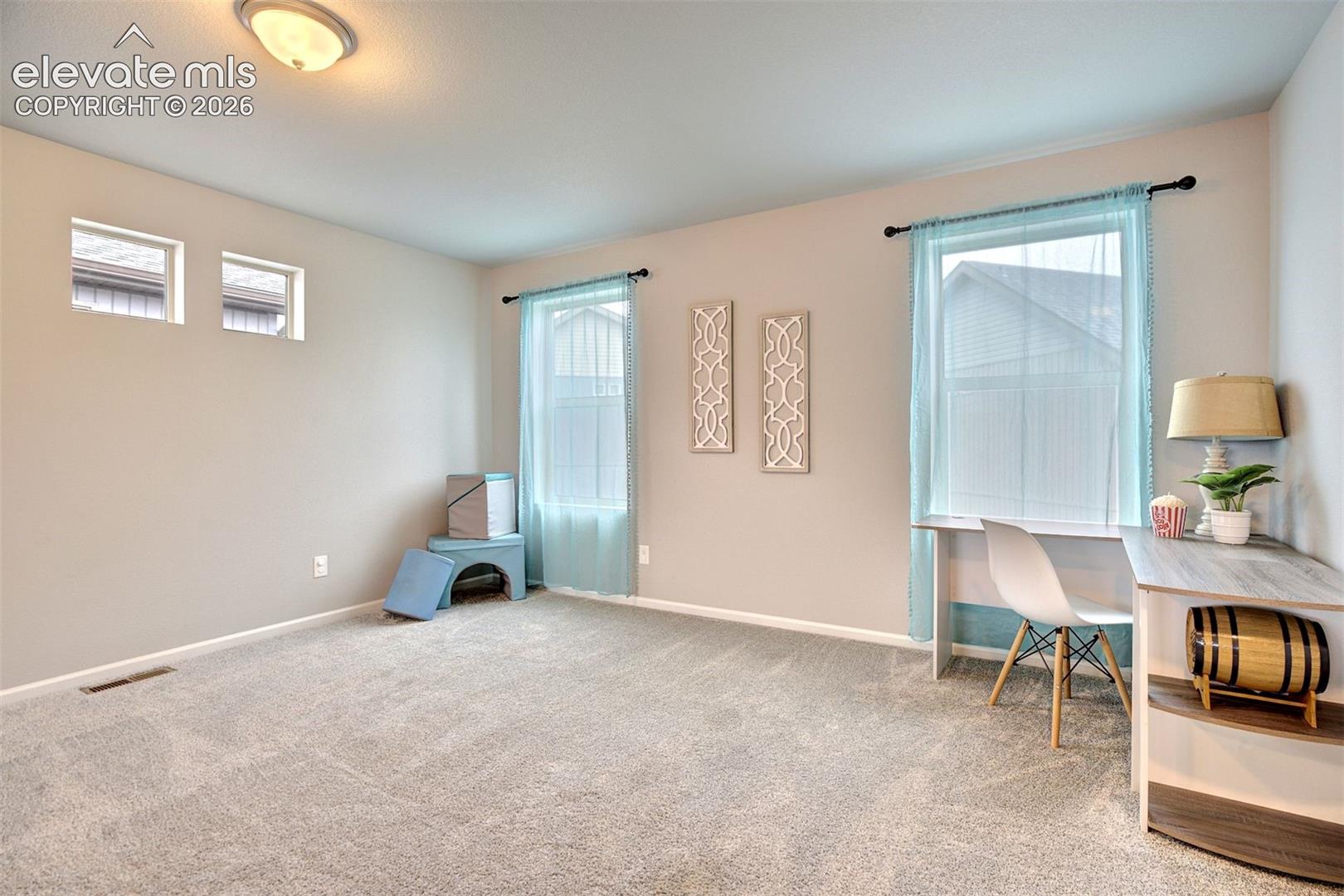 Neutral-toned interior featuring wall-to-wall carpeting, multiple windows including clerestory windows, and a flush-mount ceiling light fixture